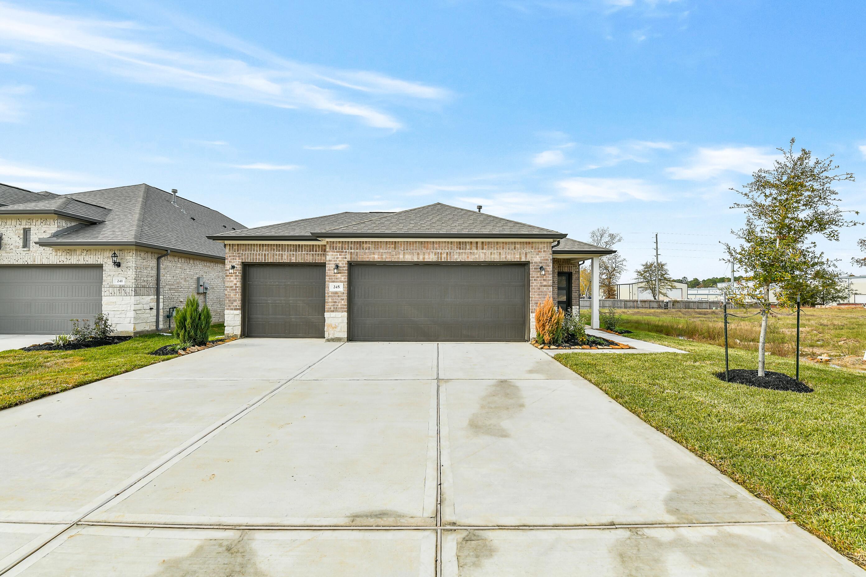 Brick single-story 4-bedroom home with 3-car garage, wide driveway, and landscaped yard in Windmill Estates, Magnolia, Texas