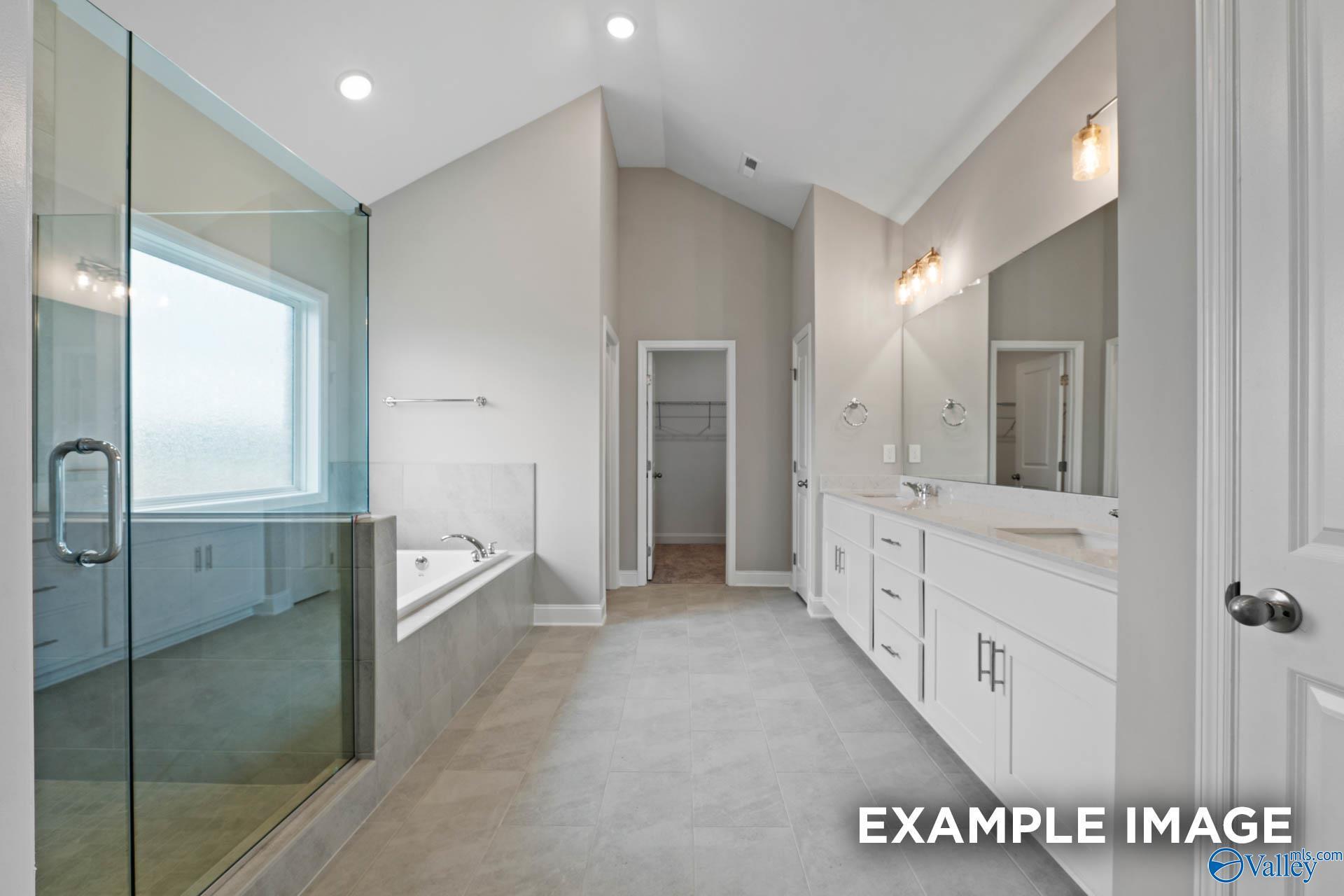 Modern master bathroom featuring frameless glass shower, soaking tub, and double vanity in Davidson Homes The Finleigh, Harvest, Alabama
