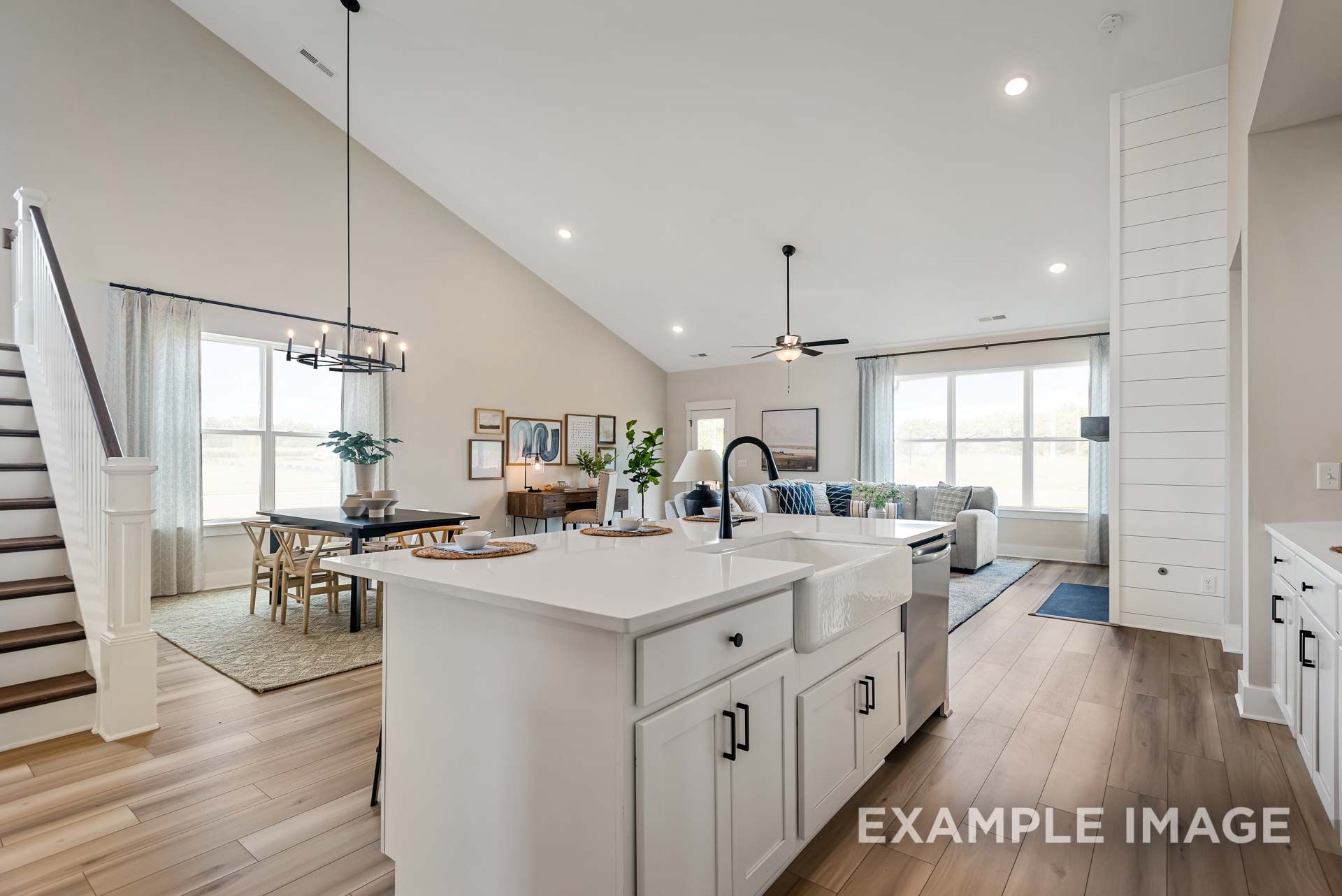 Open-concept kitchen and living area in The Ridgeport by Davidson Homes, featuring white farmhouse sink island and vaulted ceilings.