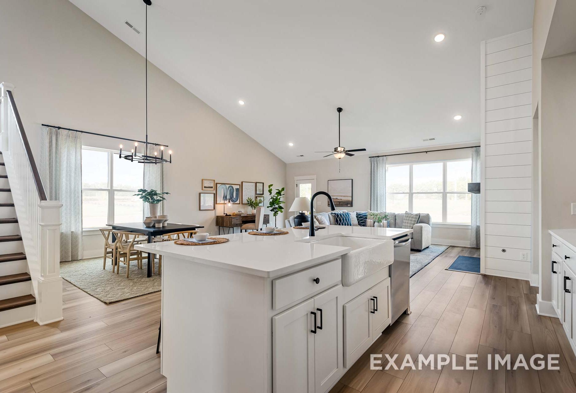 Open-concept kitchen and living area in The Ridgeport by Davidson Homes, featuring white farmhouse sink island and vaulted ceilings.