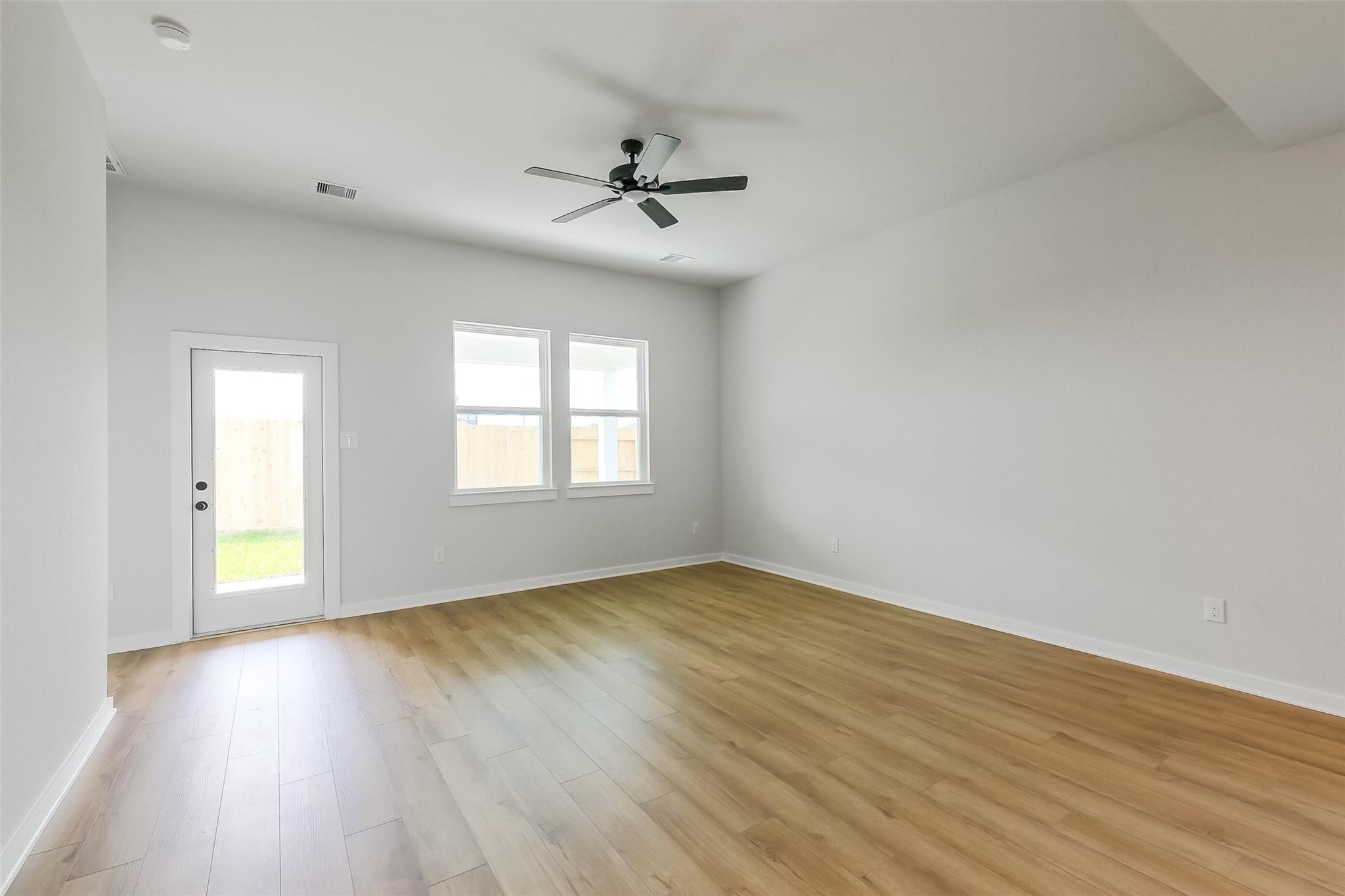 Bright living room with hardwood floors, ceiling fan, large windows and French doors in Davidson Homes The Tierra B, Beasley, Texas