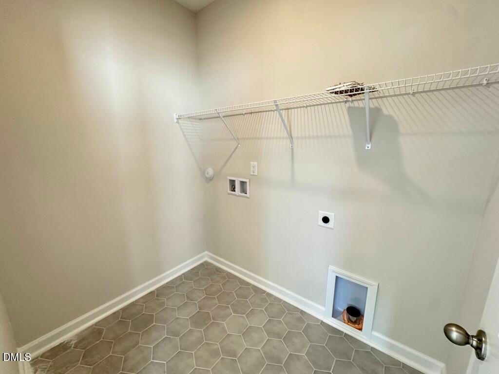 Spacious laundry room with wire shelving, washer/dryer hookups, pet door and tile flooring in Davidson Homes The Burke, Knightdale, NC