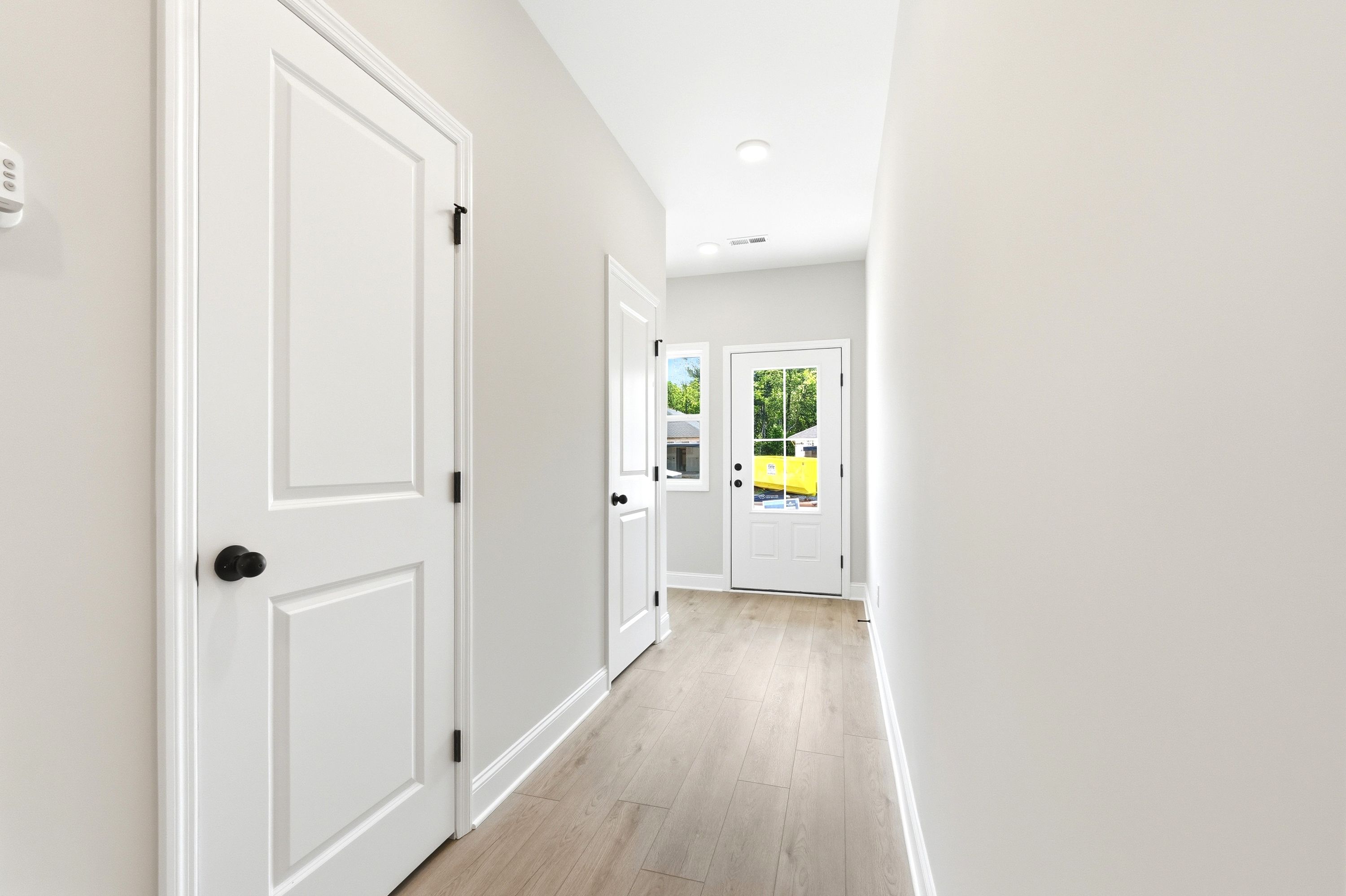Bright entryway hallway with light wood-style flooring and white interior doors in The Russell A floor plan.