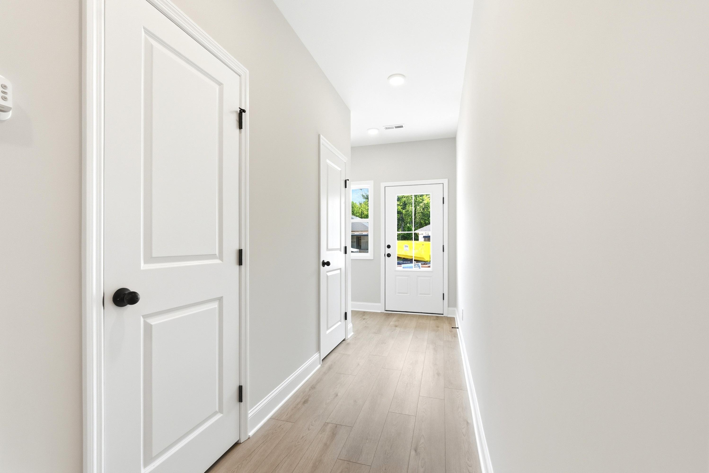 Bright entryway hallway with light wood-style flooring and white interior doors in The Russell A floor plan.