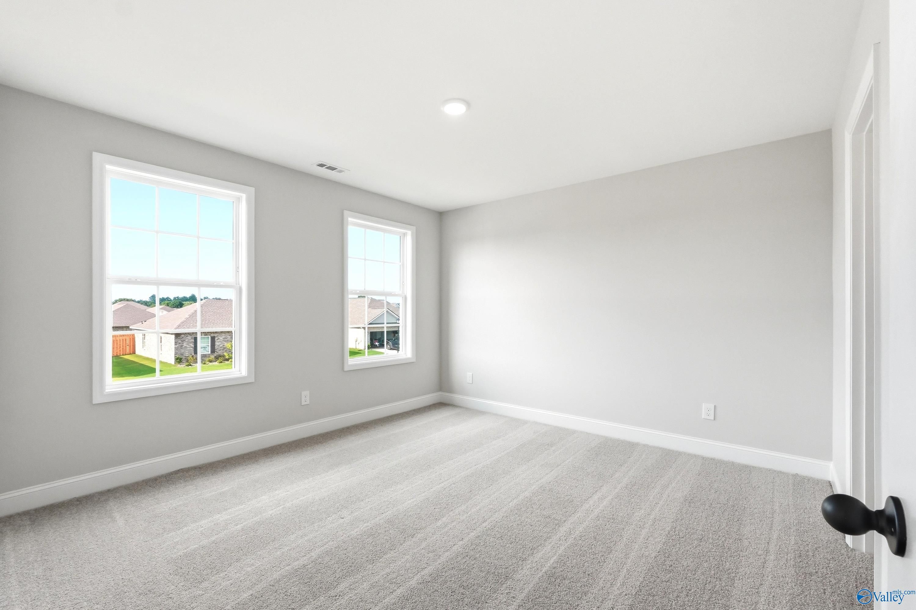 Bright, carpeted bedroom with neutral walls and windows in The Shelby A floor plan at Clearview, Hazel Green, Alabama.