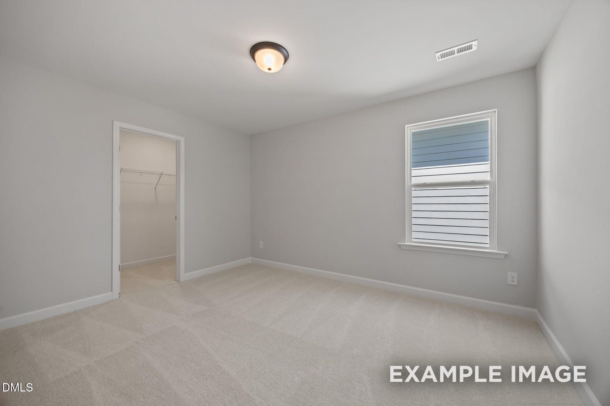 Bright empty bedroom with beige carpet, walk-in closet, and large window in Davidson Homes The Beech, Wendell Ridge, NC