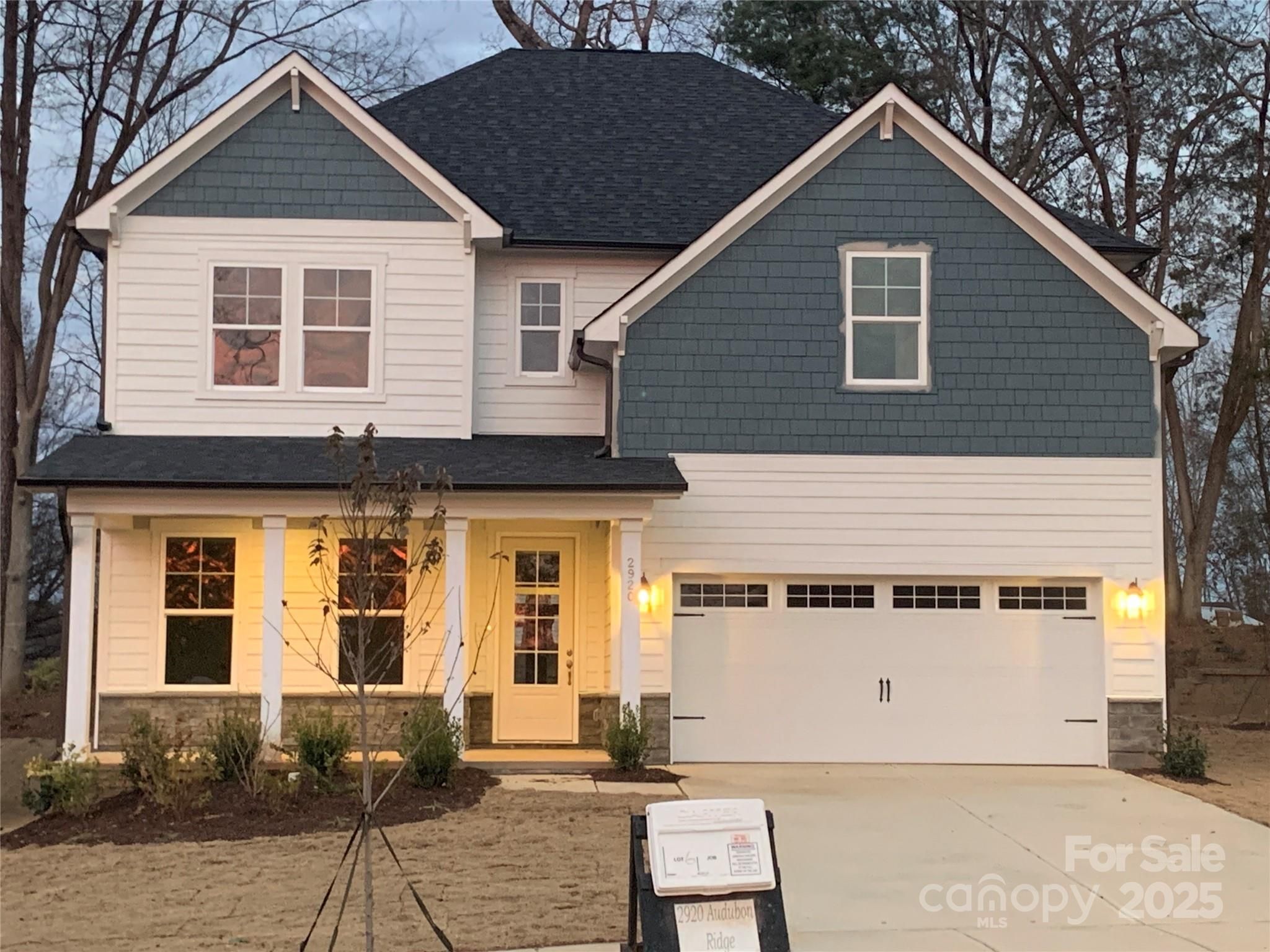 Modern two-story Hemlock A home with blue siding, white trim, two-car garage, and covered porch in Enclave at Belmont, NC
