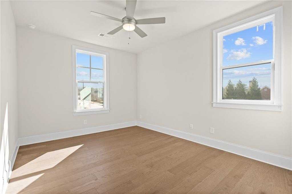 Bright bedroom featuring hardwood floors, ceiling fan, and large windows with treetop views in Davidson Homes The Arlington A, East Cobb
