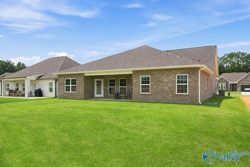 Brick exterior and covered patio of Davidson Homes The Harrison floor plan with large backyard in Cain Park, Hartselle, Alabama