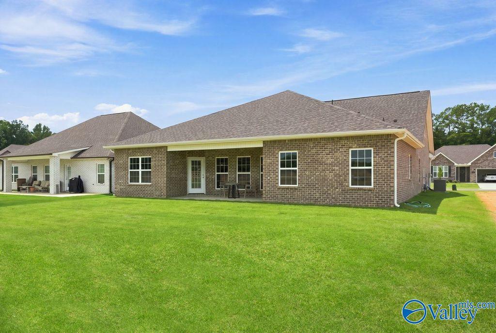Brick exterior and covered patio of Davidson Homes The Harrison floor plan with large backyard in Cain Park, Hartselle, Alabama