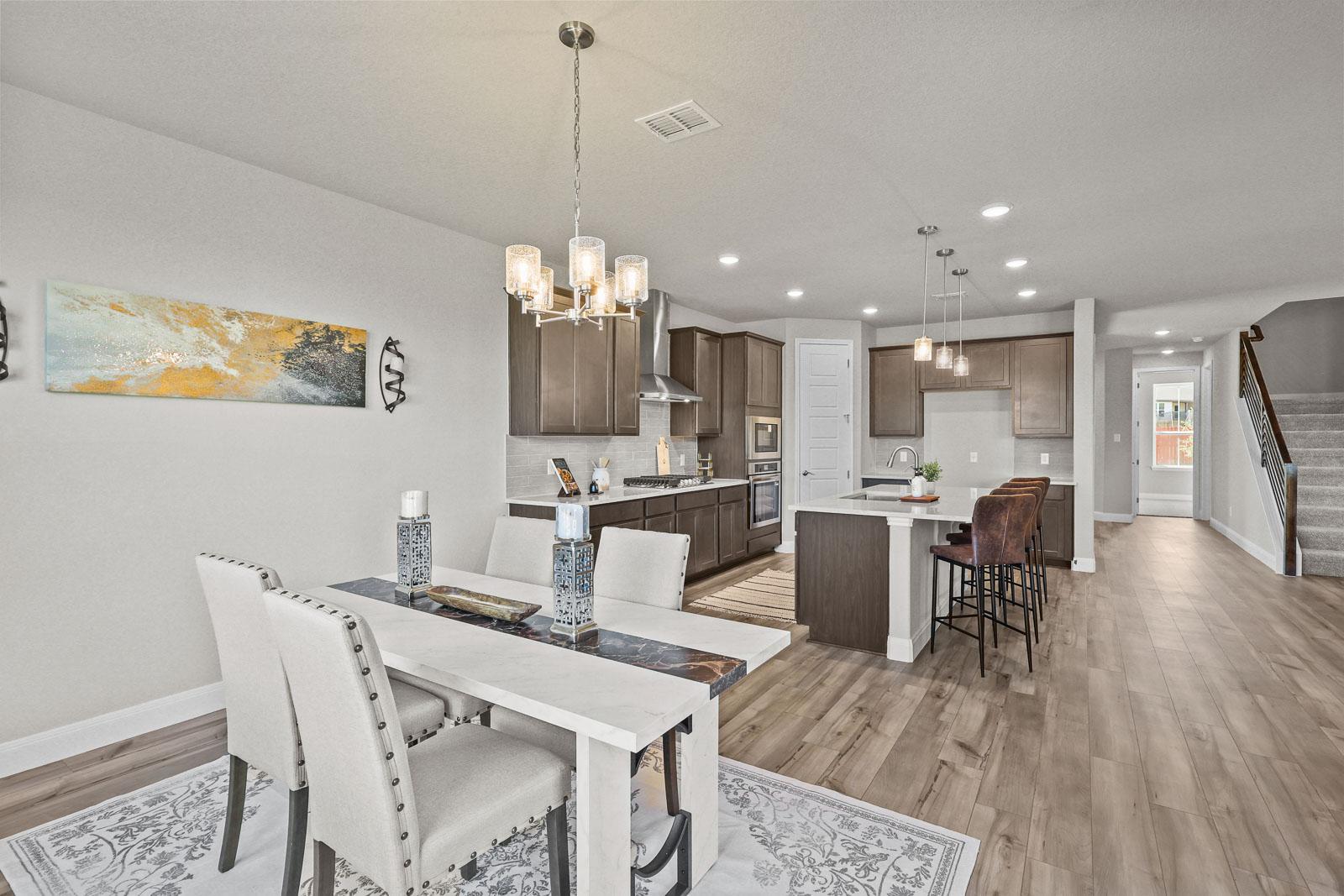 Open-concept kitchen and dining area in The Jennings G featuring modern cabinetry, a center island, and wood-style flooring.