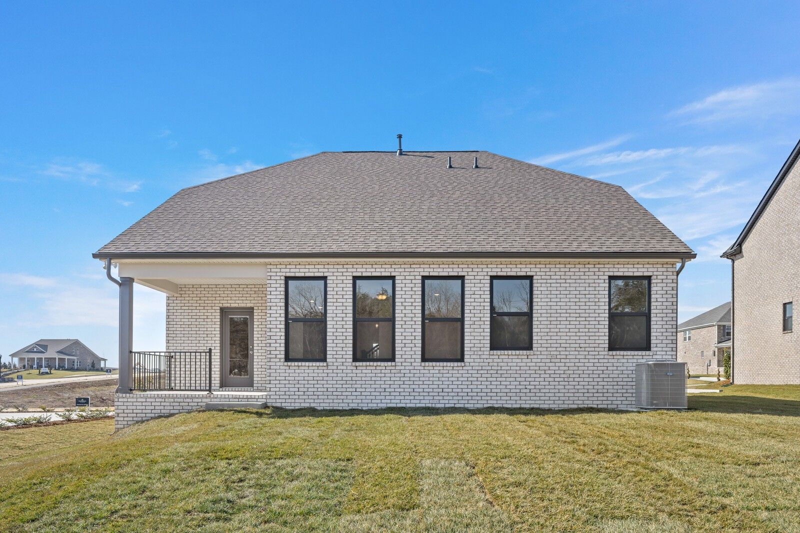 Two-story beige brick home with gabled roof, covered porch, and large black-framed windows in Benders Cove, Mt. Juliet, TN - Davidson Homes The Ash C