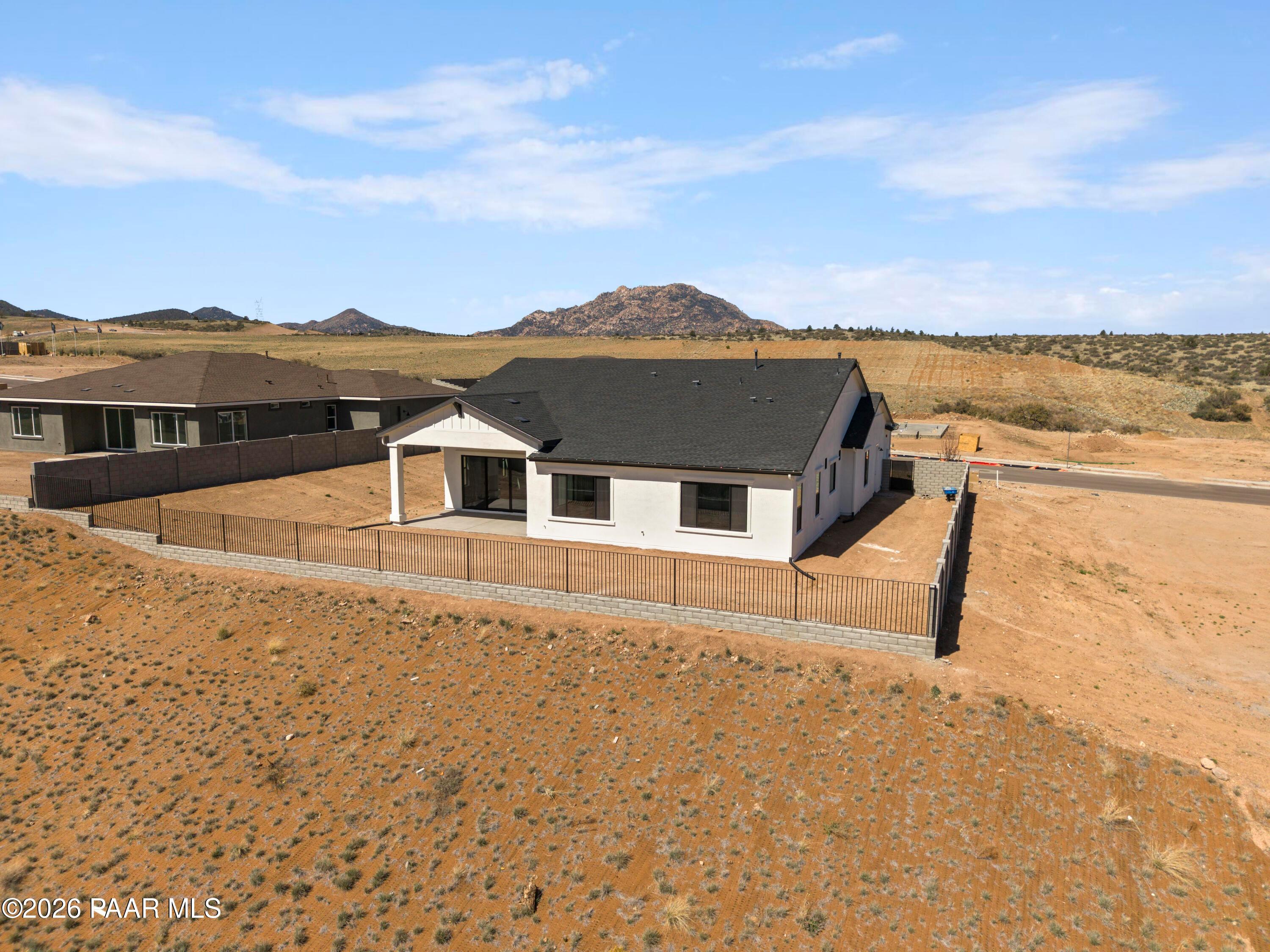 Modern single-story Davidson Homes Soleil E with 3-car garage, white stucco exterior, fenced desert yard, mountain backdrop in Hidden Hills, Prescott, AZ