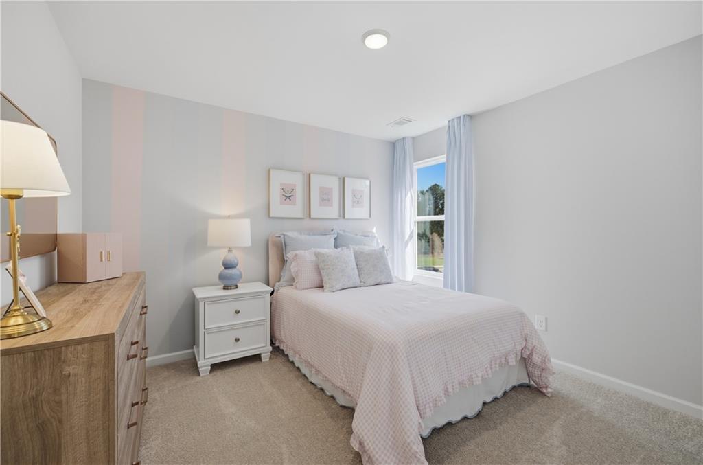 Bright bedroom with pastel bedding, white nightstand, and window in Davidson Homes The Sinclair B, Greene Farm, Cartersville, Georgia