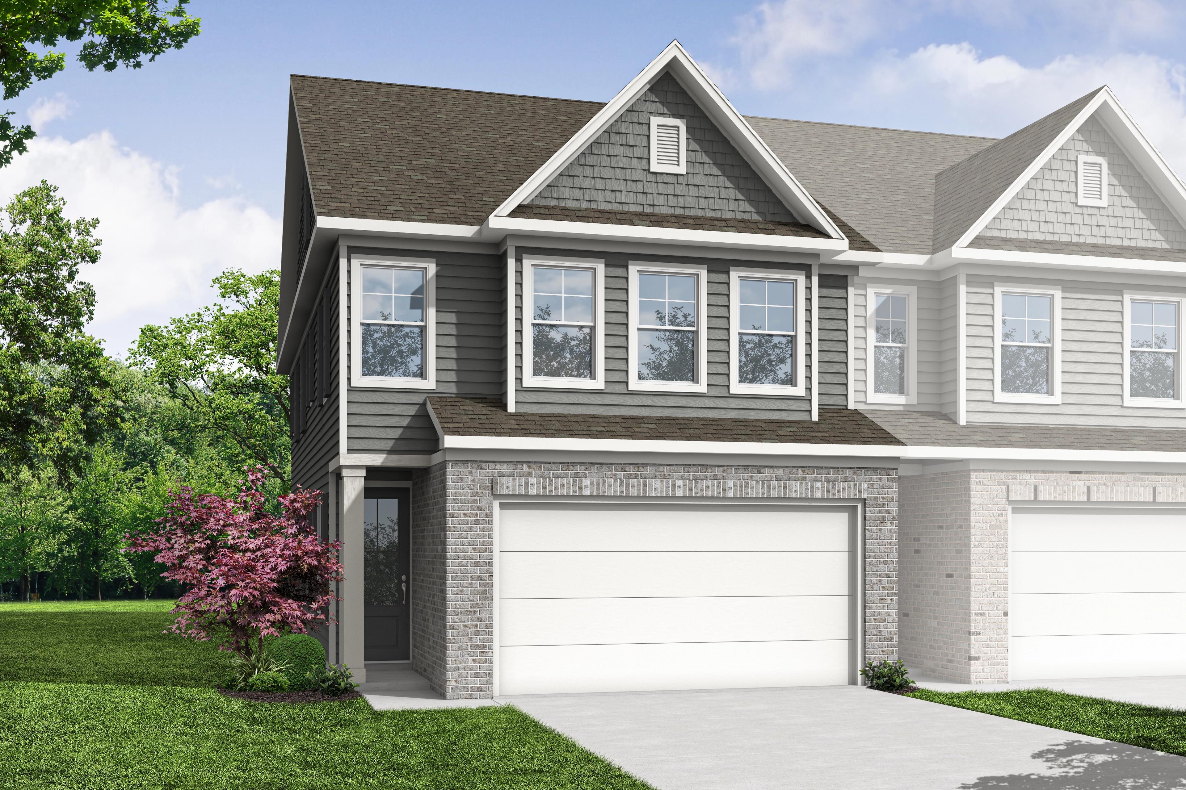 The Wake B multi-family duplex in Cumming GA: 2-story units with gray siding, brick accents, 2-car garages, and tree-lined front yard