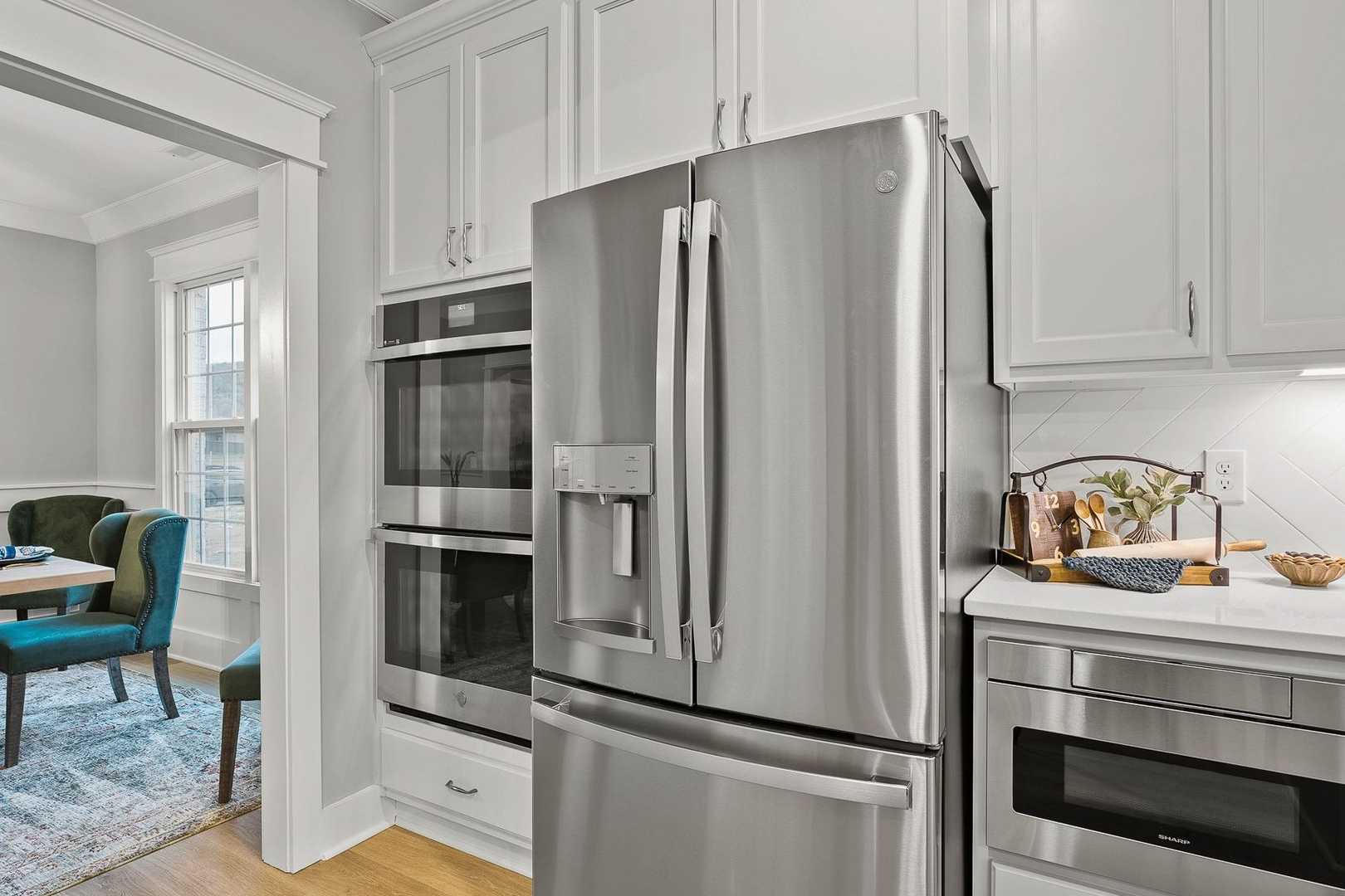 Spacious Oxford kitchen with white shaker cabinets, stainless steel French door fridge, double ovens, and open dining area with blue chairs