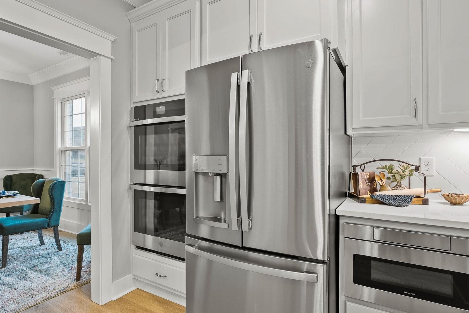 Spacious Oxford kitchen with white shaker cabinets, stainless steel French door fridge, double ovens, and open dining area with blue chairs