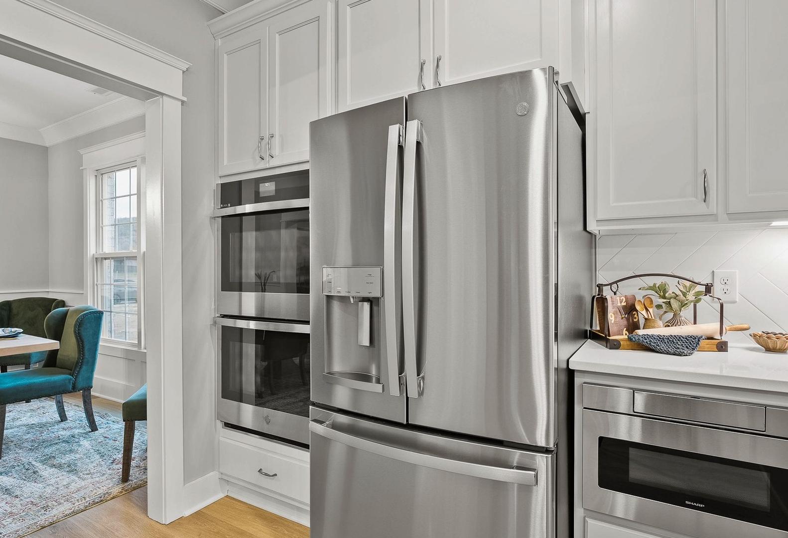 Spacious Oxford kitchen with white shaker cabinets, stainless steel French door fridge, double ovens, and open dining area with blue chairs