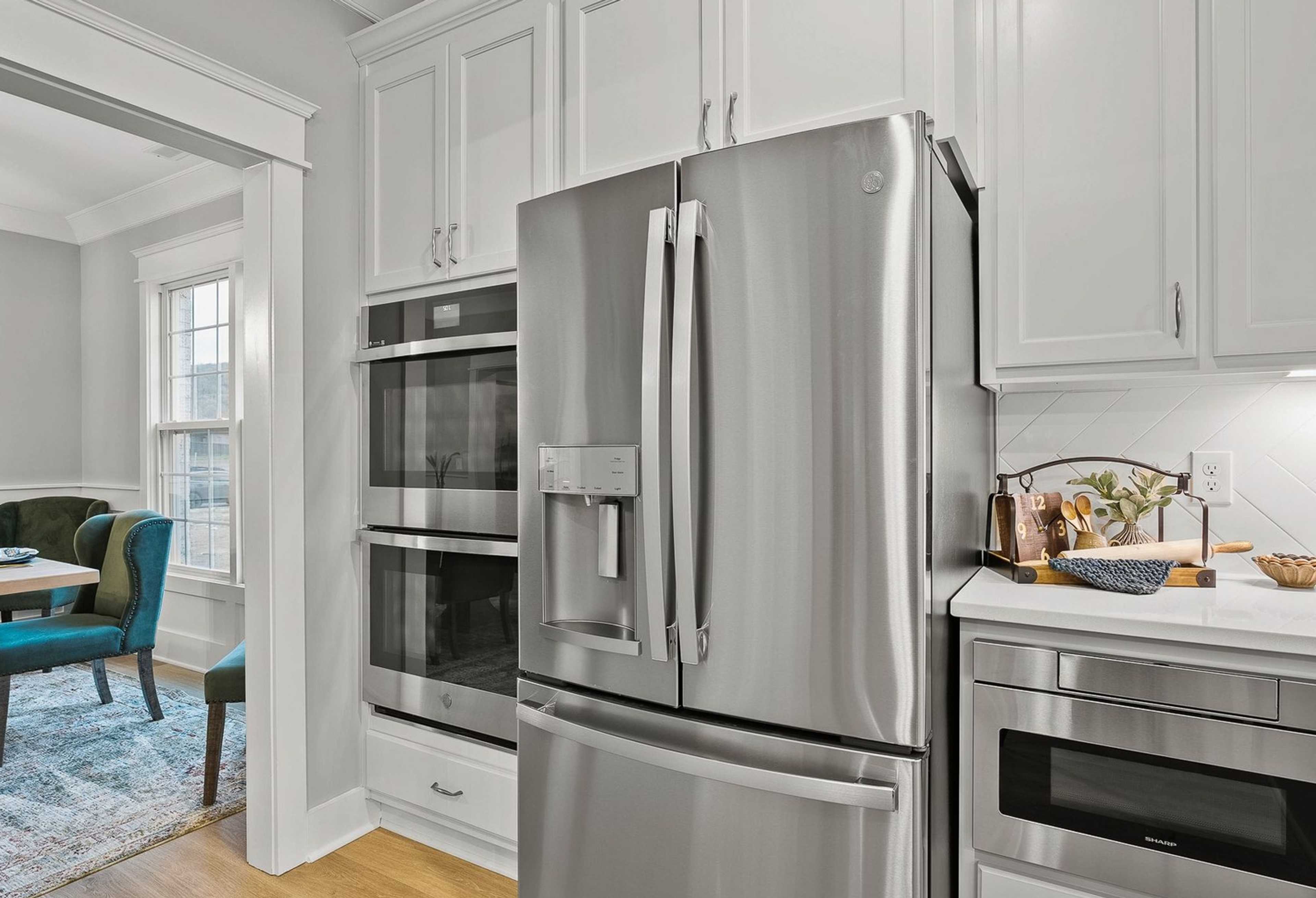 Spacious Oxford kitchen with white shaker cabinets, stainless steel French door fridge, double ovens, and open dining area with blue chairs