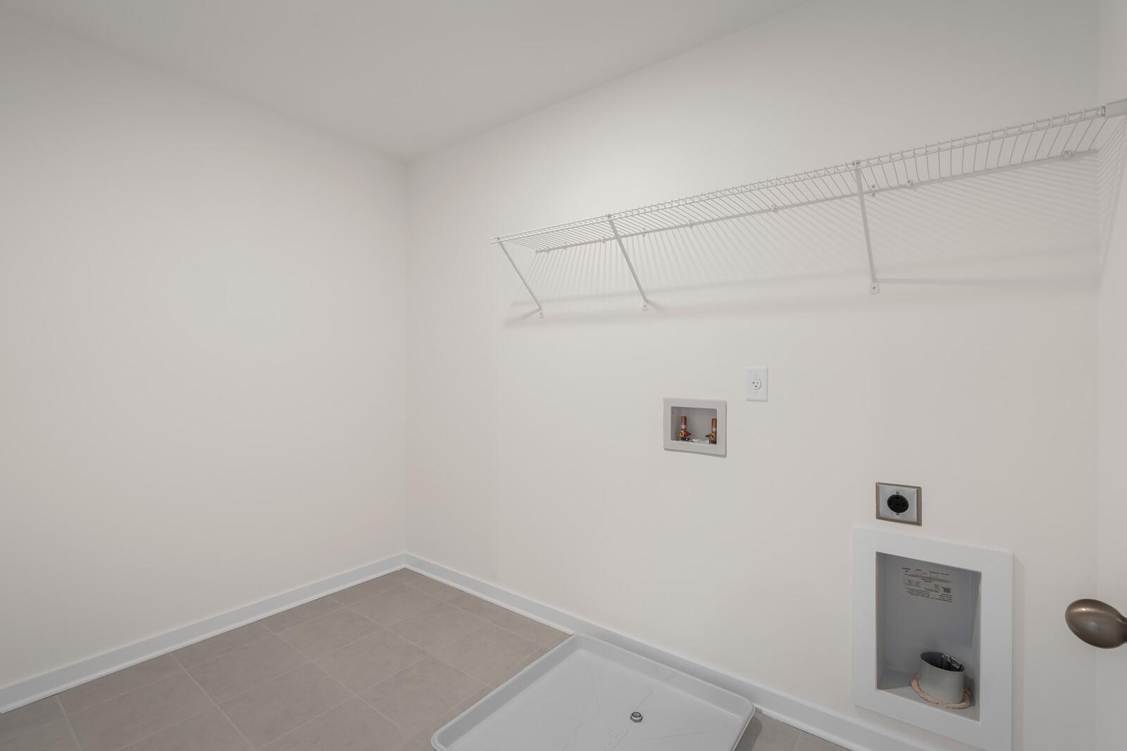 Laundry room with wire shelving and utility hookups in The Willow floor plan at Woods Crossing, Gallatin, Tennessee.
