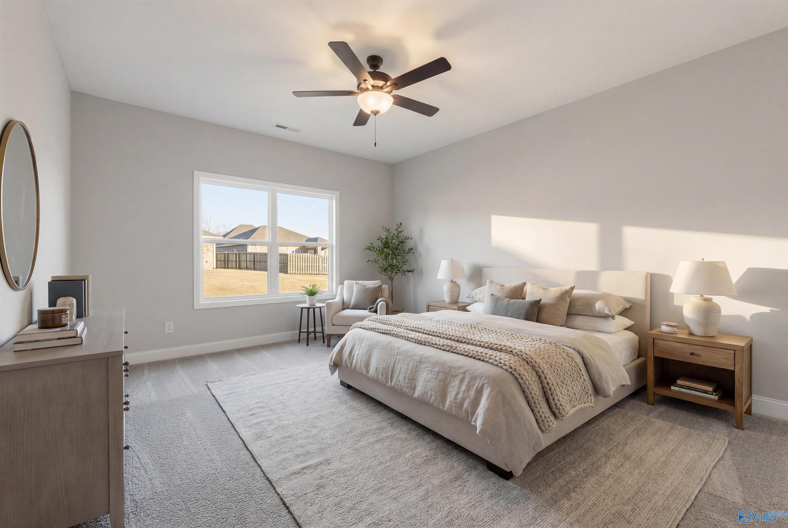 Serene master bedroom with king bed, neutral linens, ceiling fan, and large window in Davidson Homes The Daphne D, Arab, Alabama