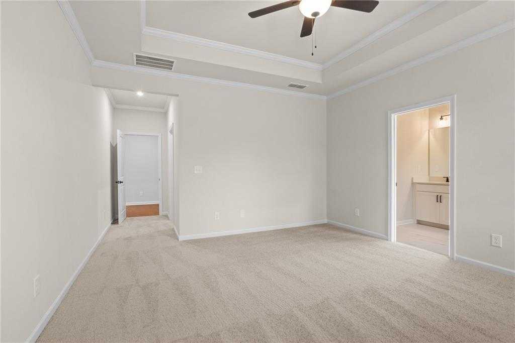Spacious master bedroom with tray ceiling, ceiling fan, and en-suite bath featuring double vanity in Davidson Homes The Glenwood A, Loganville, GA
