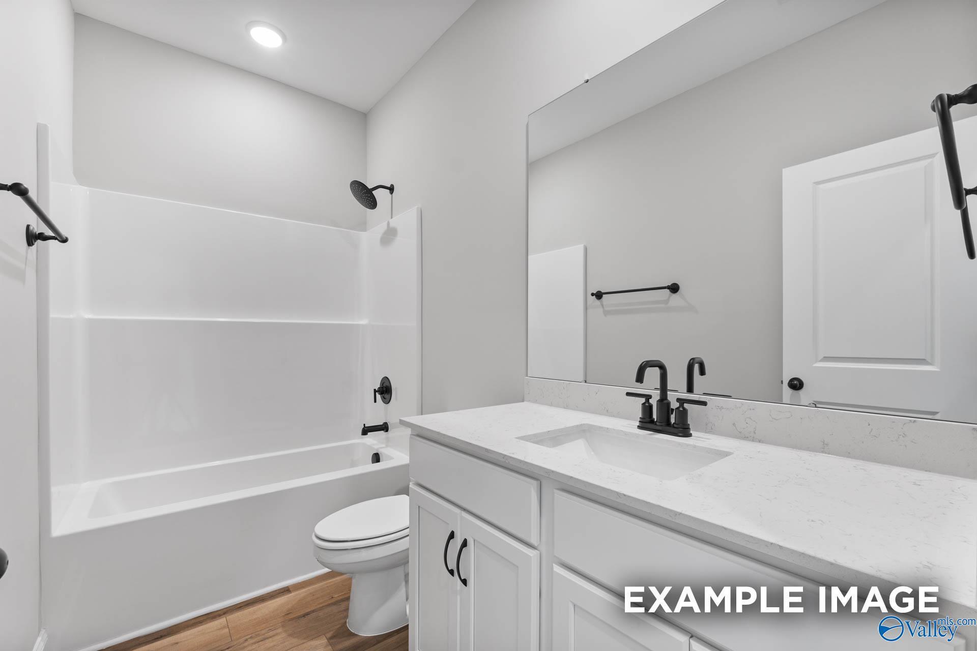 Modern guest bathroom featuring white tub-shower combo, double-sink vanity, and large mirror in The Asheville C, Hazel Green, Alabama