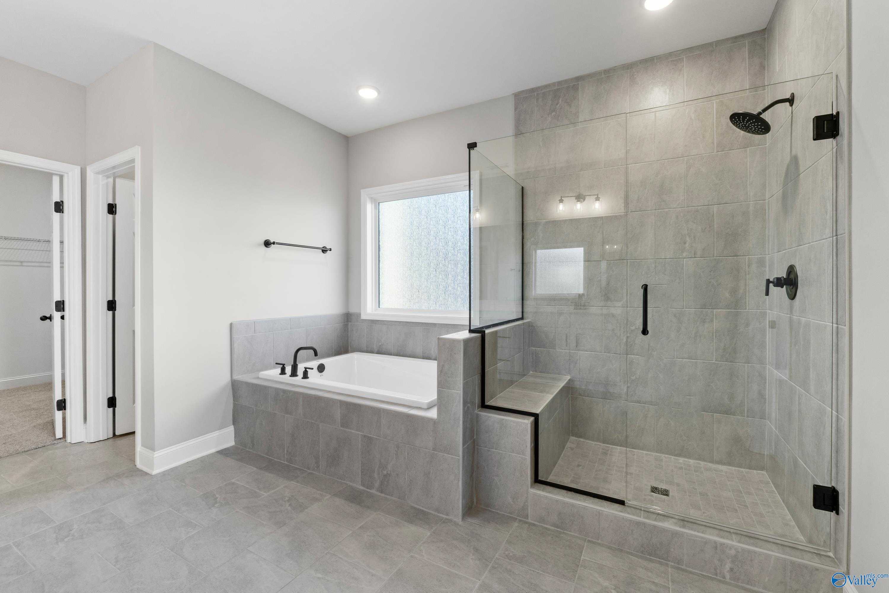Luxurious master bath with freestanding tub, glass shower, and gray tiles in Davidson Homes The Valencia, Meridianville, Alabama