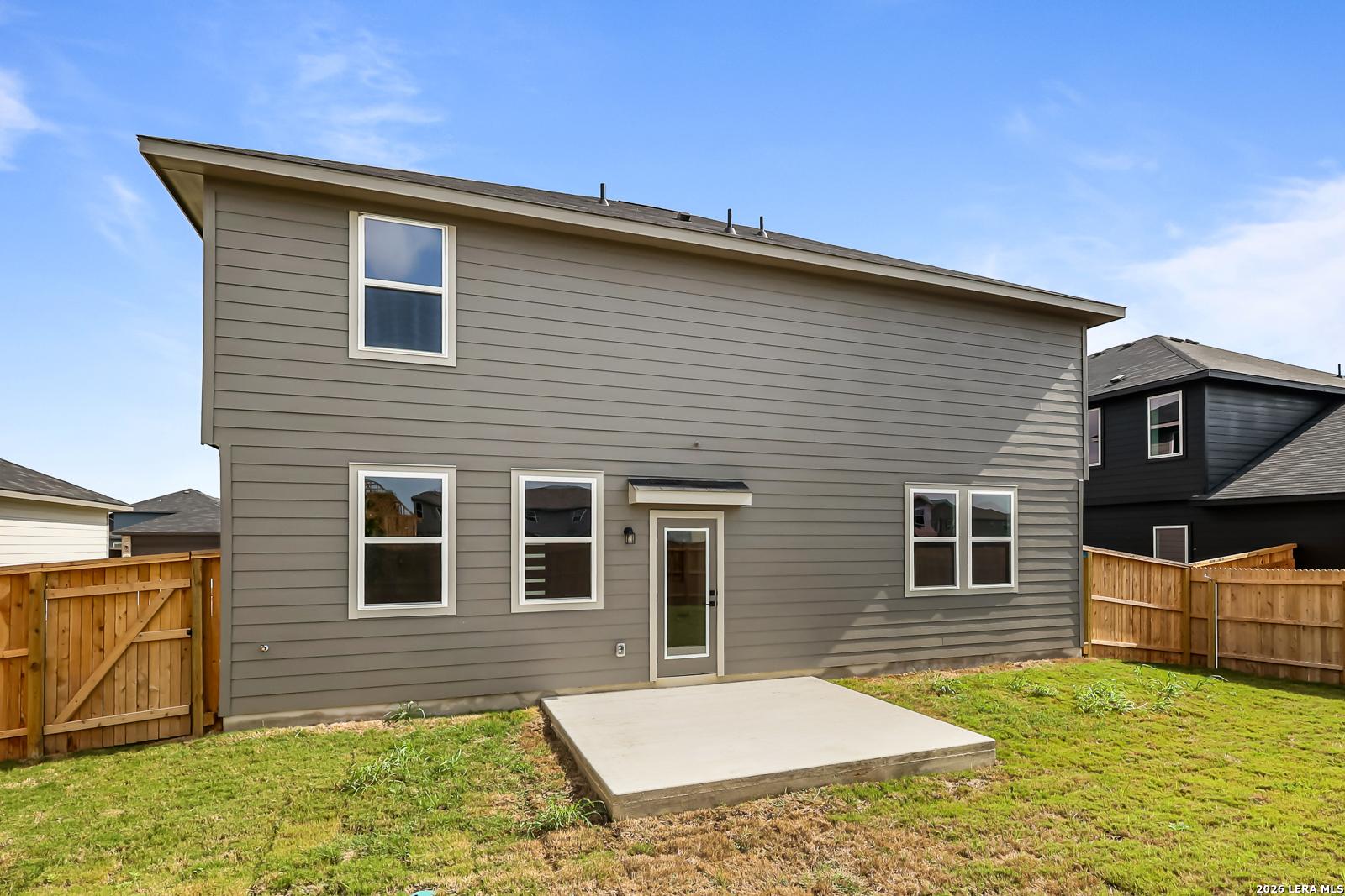 Rear view of 2-story Davidson Homes Douglas C floor plan with concrete patio and wood fence in Hannah Heights, Seguin, TX.