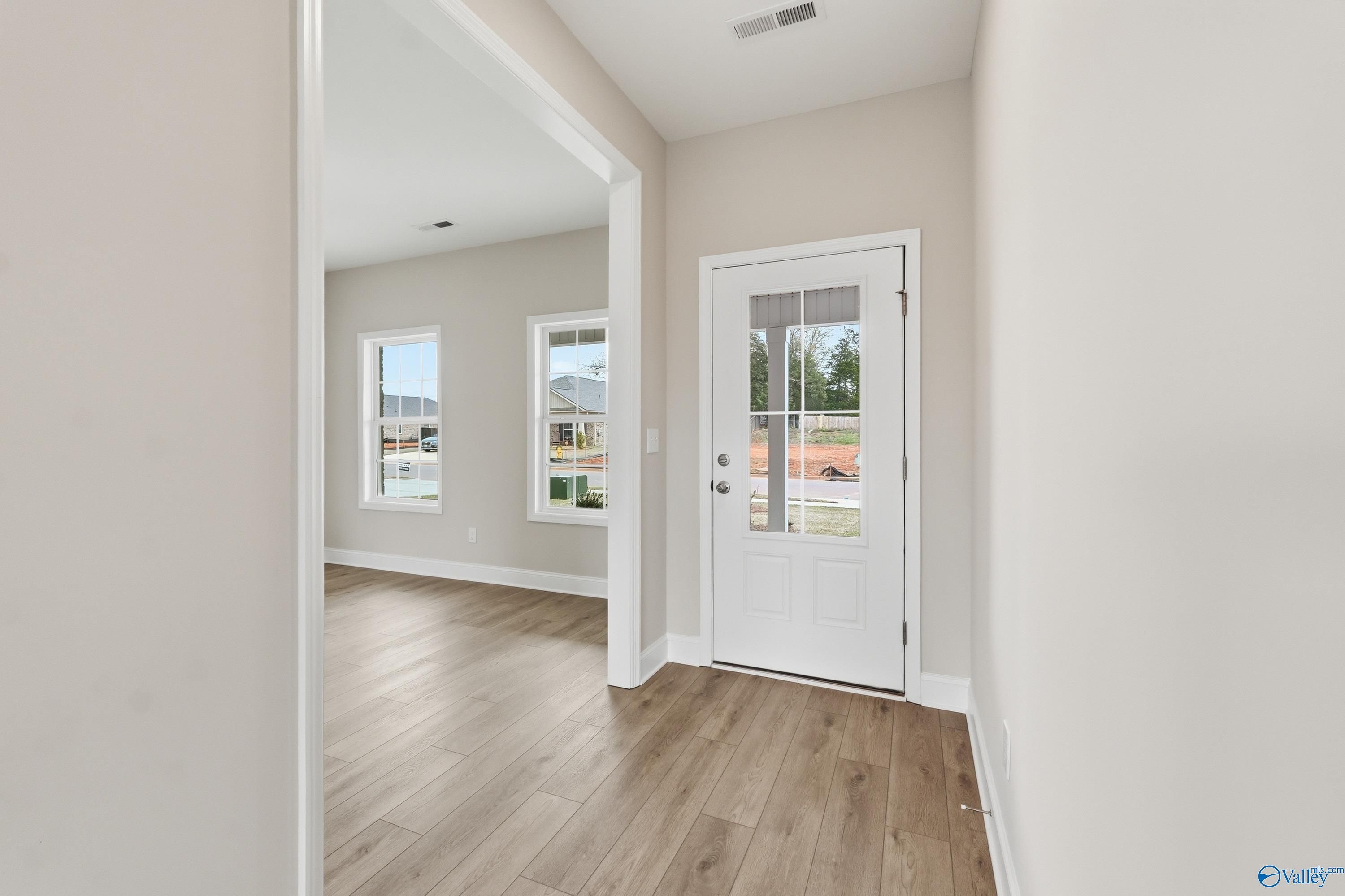 Bright entryway with beige walls, wood floors, and glass door in Davidson Homes The Shelby B, New Market, Alabama