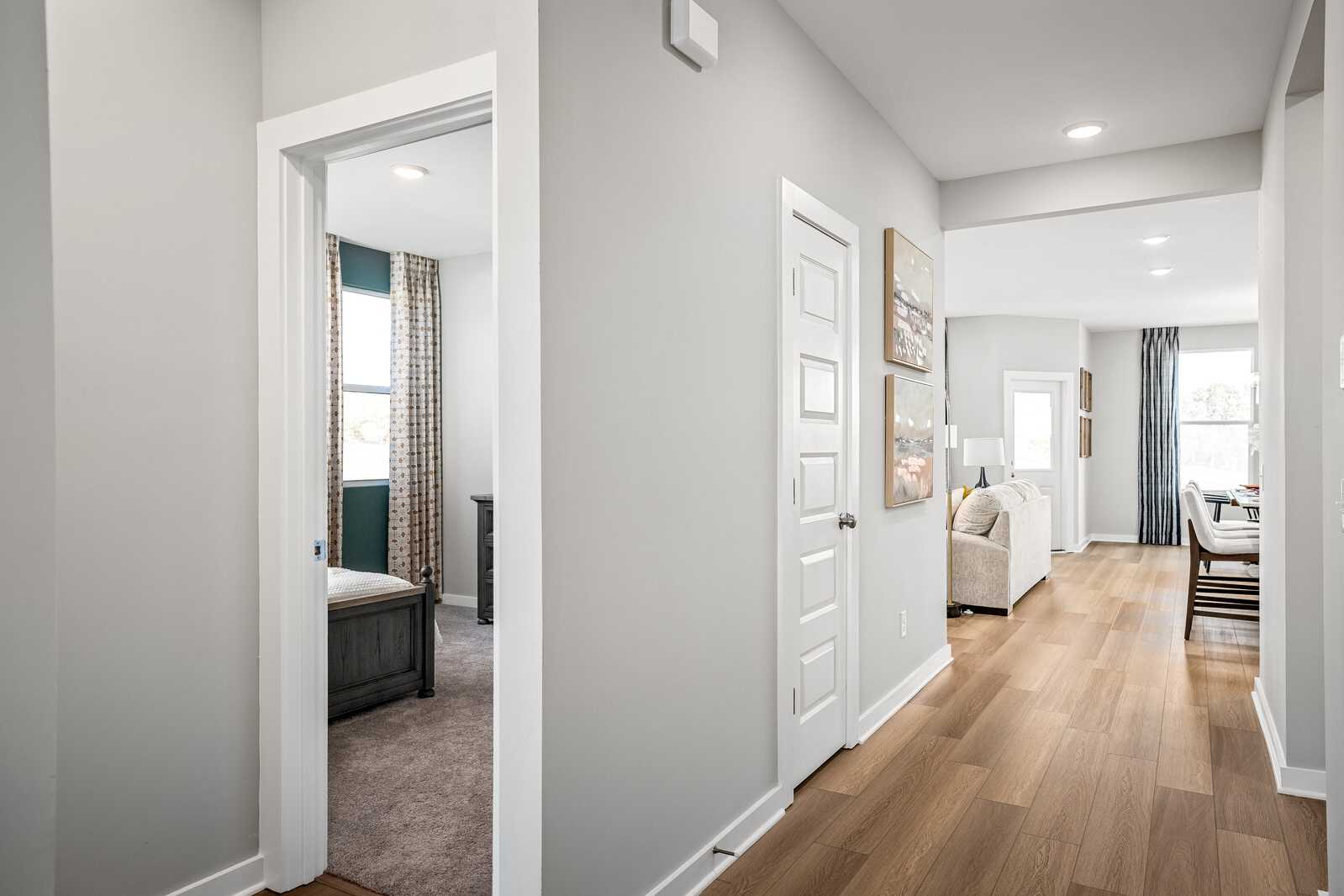 Spacious gray hallway with bedroom view in Sage Farms home, White House TN by Davidson Homes featuring hardwood floors and open living area