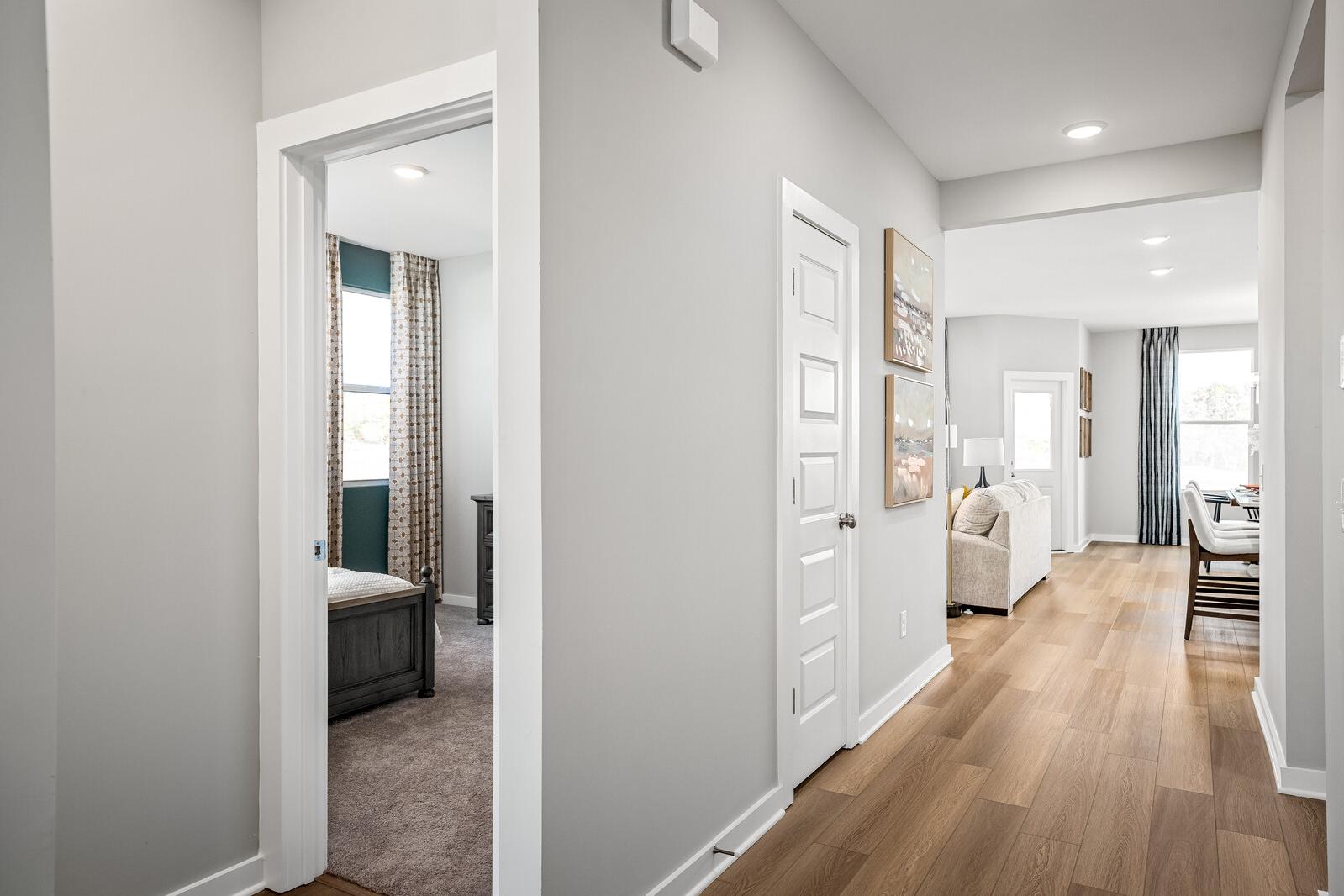 Spacious gray hallway with bedroom view in Sage Farms home, White House TN by Davidson Homes featuring hardwood floors and open living area