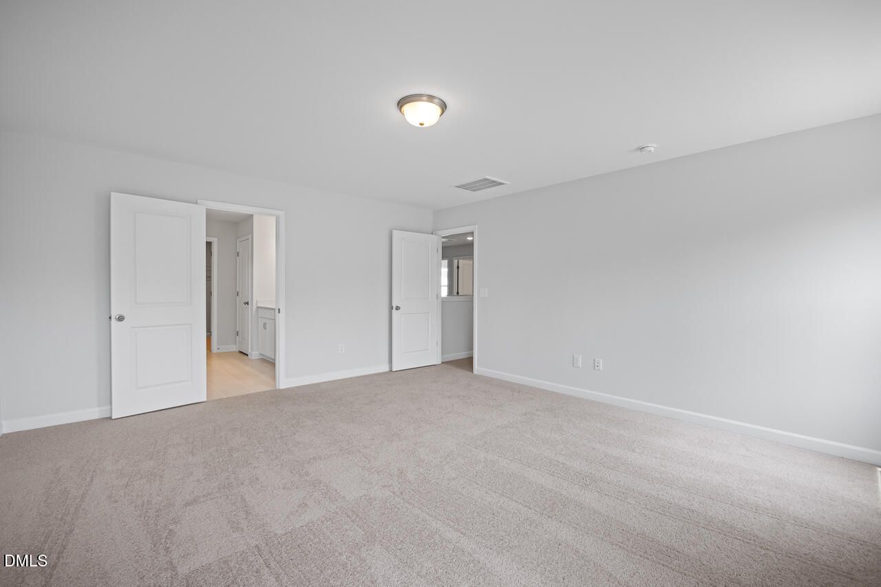 Spacious secondary bedroom with attached bath, beige carpet, and white walls in Davidson Homes The Hickory II B, Zebulon, NC