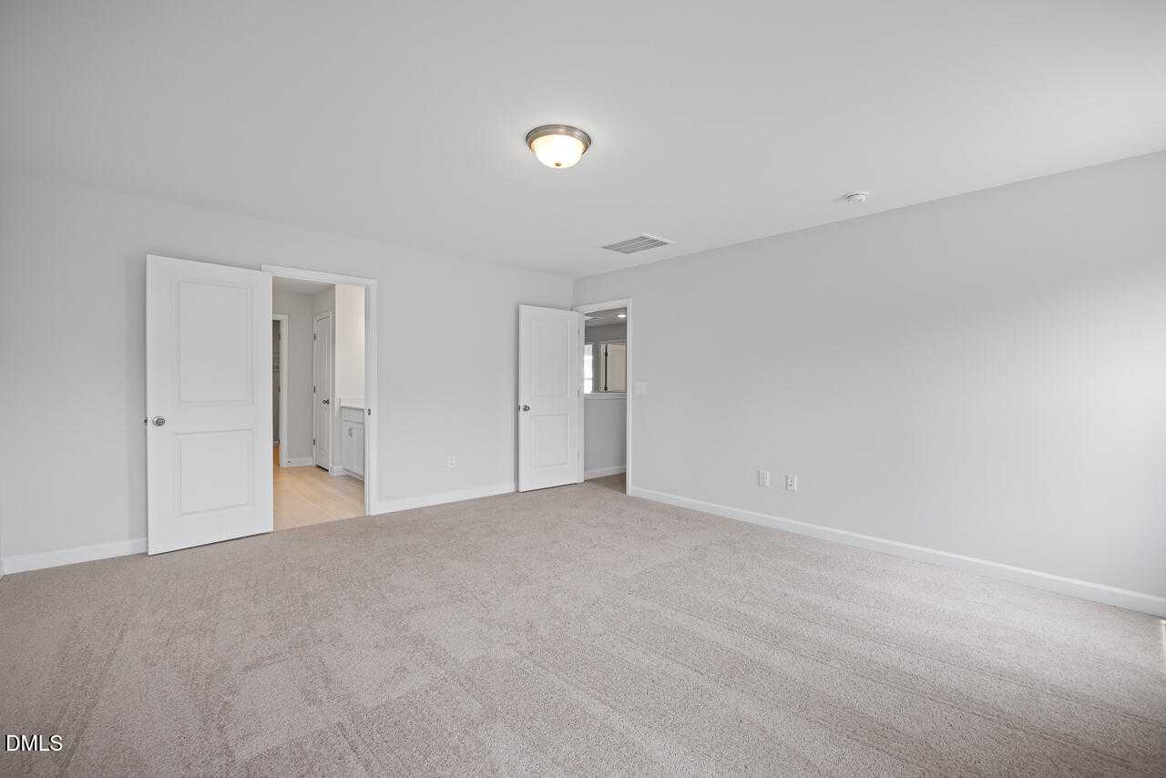 Spacious secondary bedroom with attached bath, beige carpet, and white walls in Davidson Homes The Hickory II B, Zebulon, NC