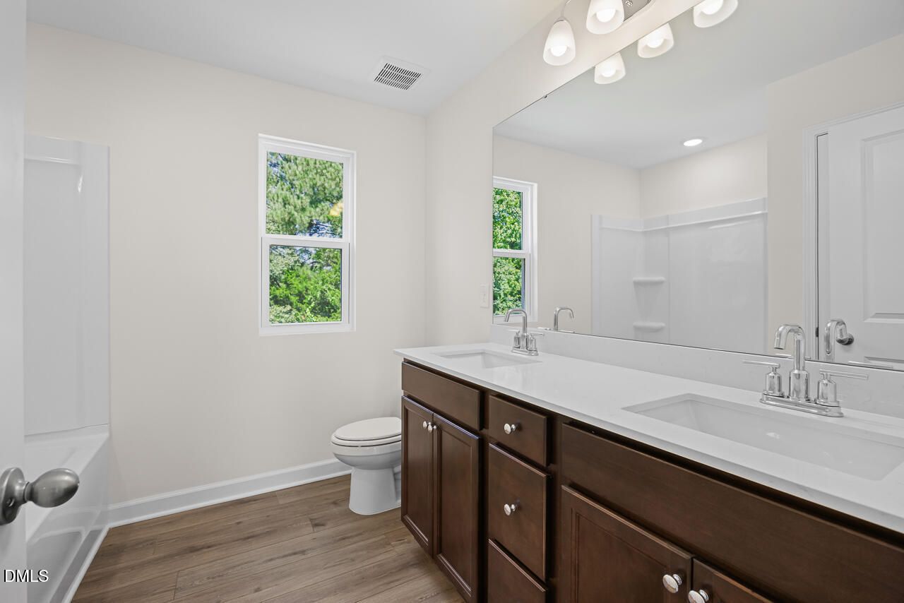 Double vanity bathroom with dark wood cabinets and white countertops in The Willow B plan at Woodland Crossing, Zebulon, NC