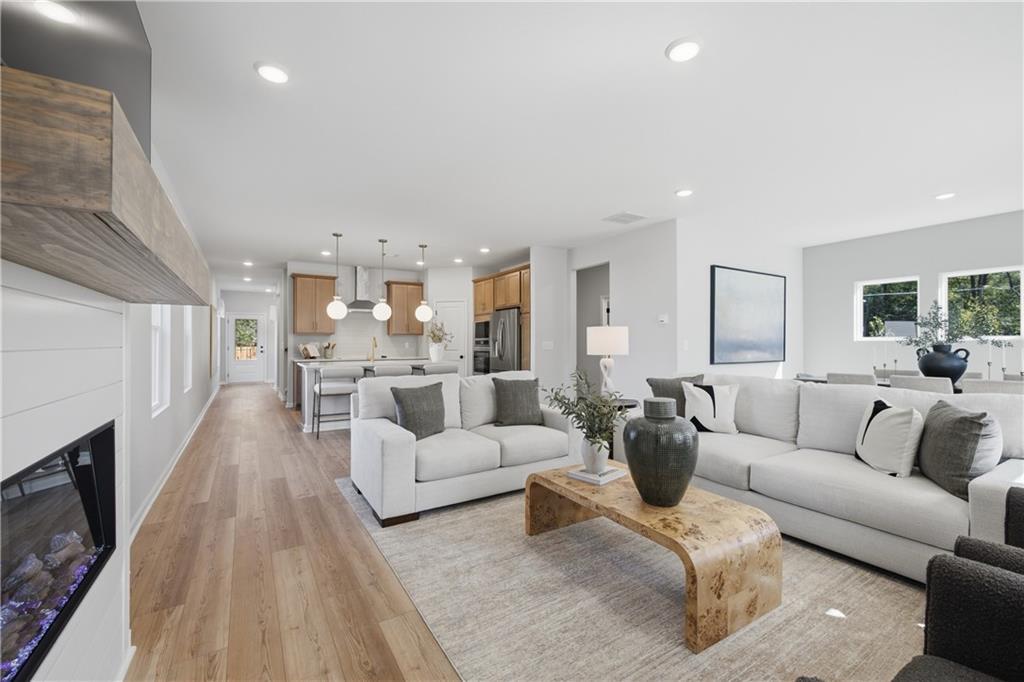 Open-concept great room with fireplace, white sofas, and hardwood floors in Davidson Homes The Sinclair B, Cartersville, Georgia