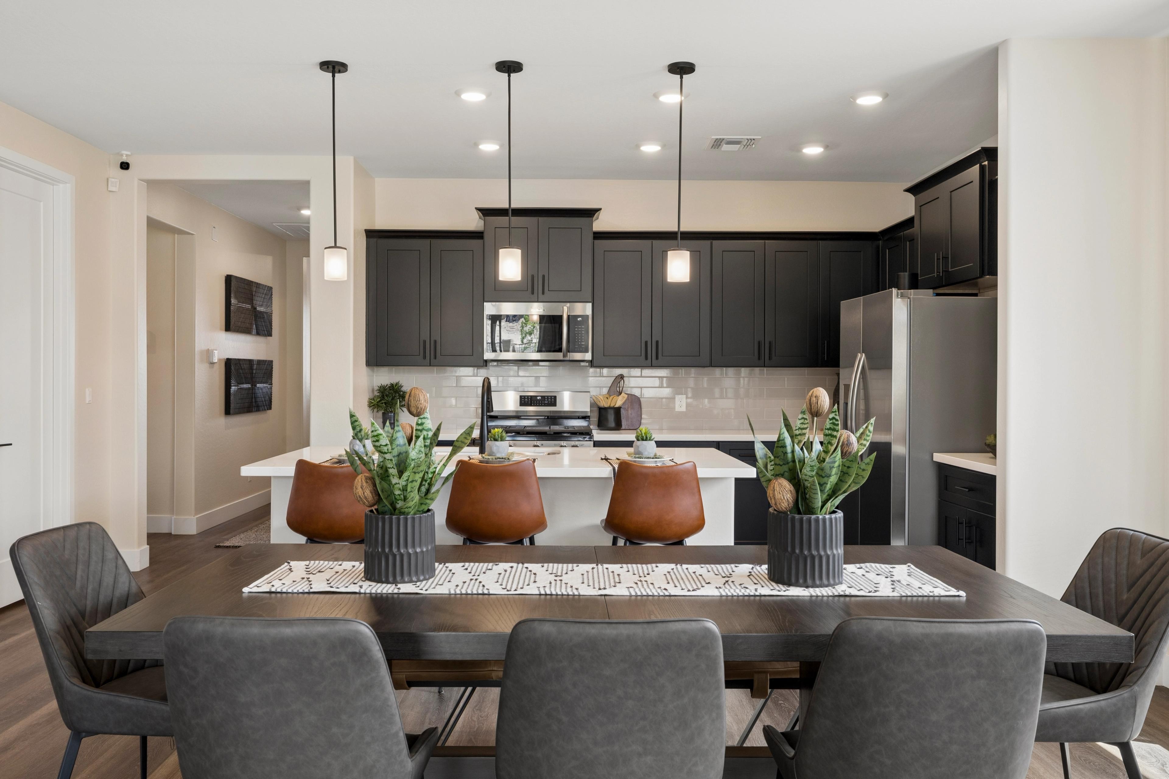 Spacious modern kitchen dining area at South Ranch Western Collection in Prescott AZ with dark gray cabinets white quartz island pendant lights and succulent plants
