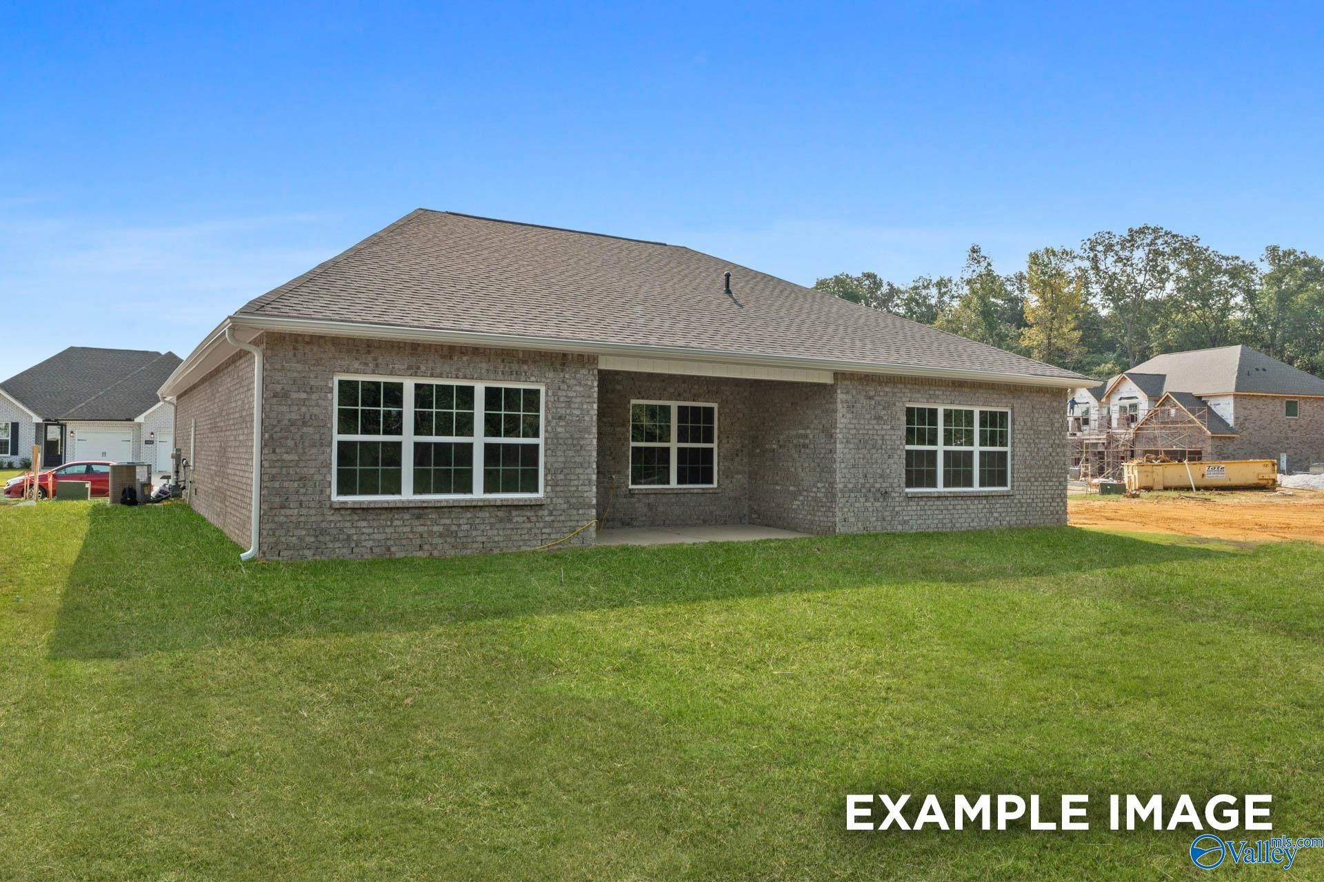 Brick single-story home with gabled roof, covered porch, large windows, and green lawn in Kendall Downs, Toney, Alabama