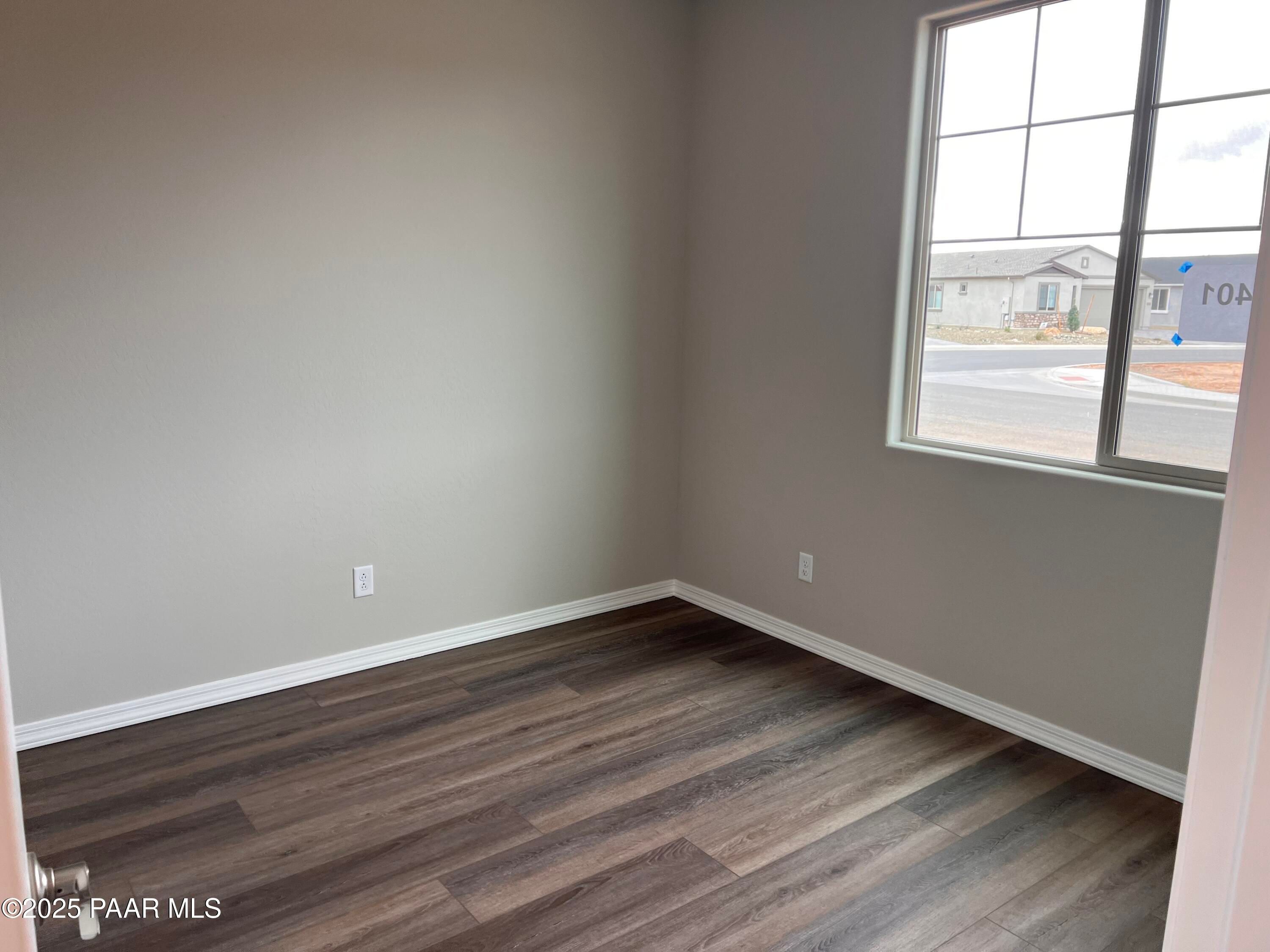 Empty bedroom with light gray walls, large window viewing neighborhood, luxury vinyl plank flooring in Davidson Homes The Harmony A, Prescott Valley AZ