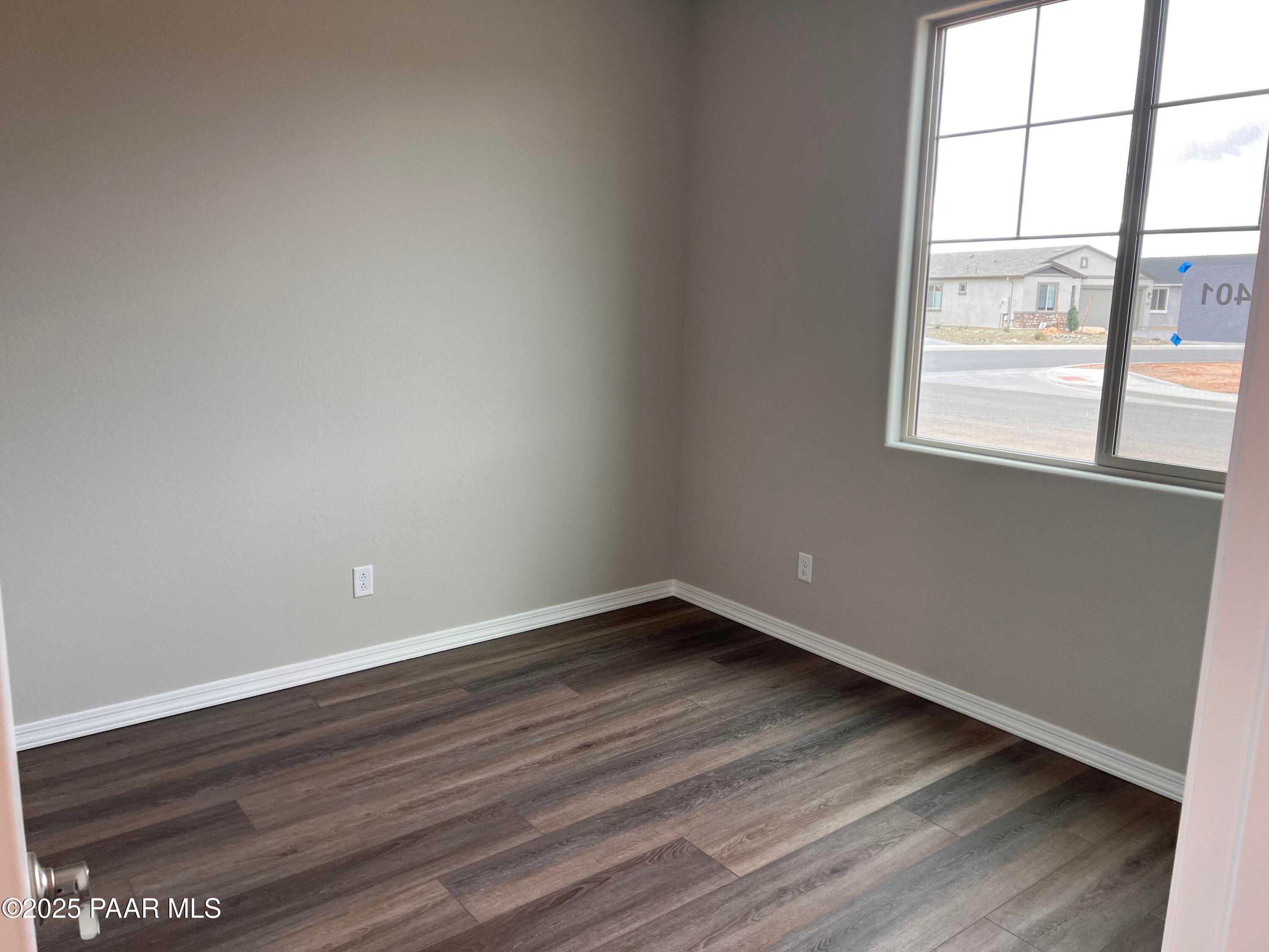 Empty bedroom with light gray walls, large window viewing neighborhood, luxury vinyl plank flooring in Davidson Homes The Harmony A, Prescott Valley AZ