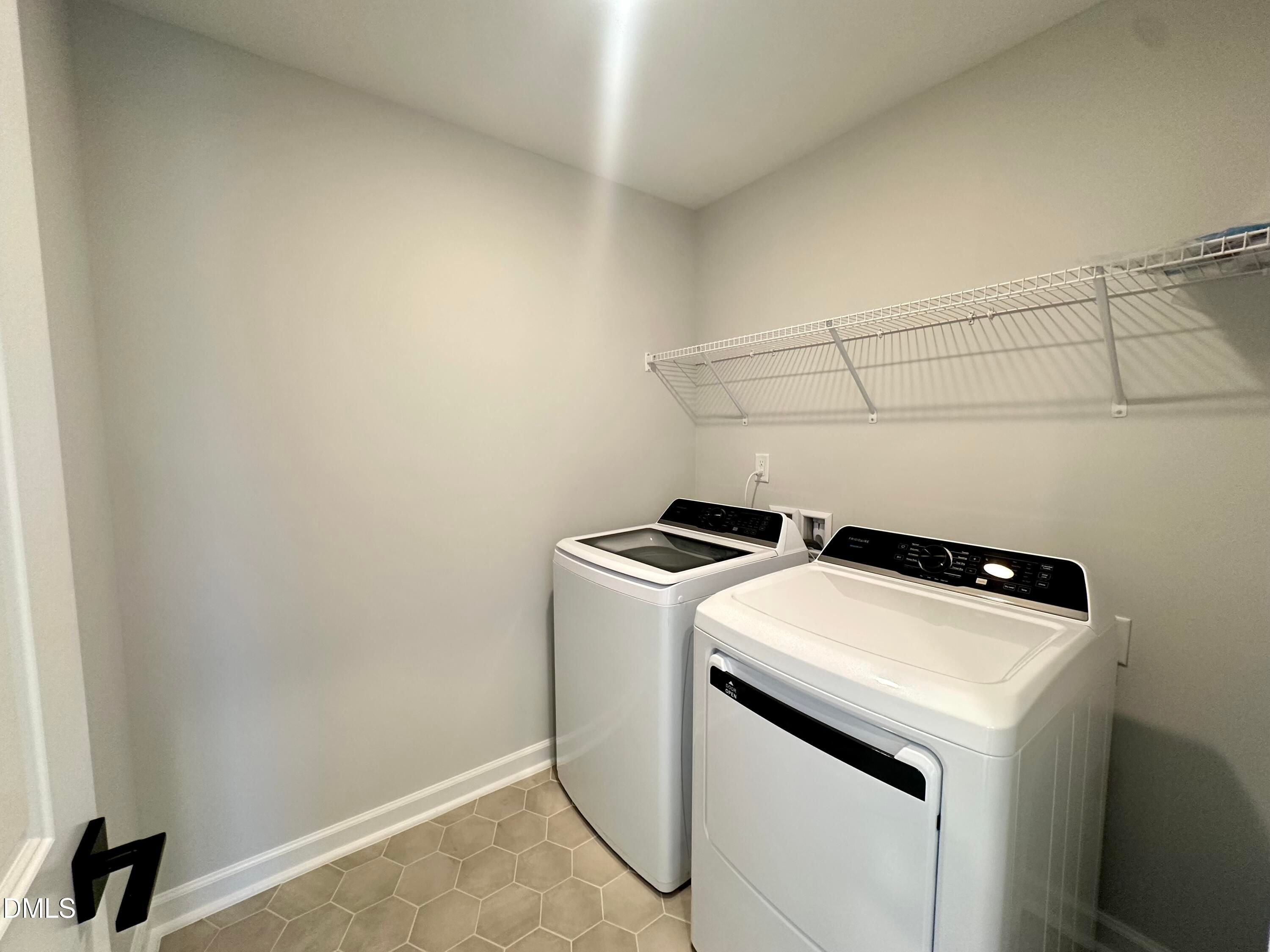 Modern laundry room with white front-load washer, dryer, wire shelving, hex tile floor in Davidson Homes The Avery, Knightdale, NC