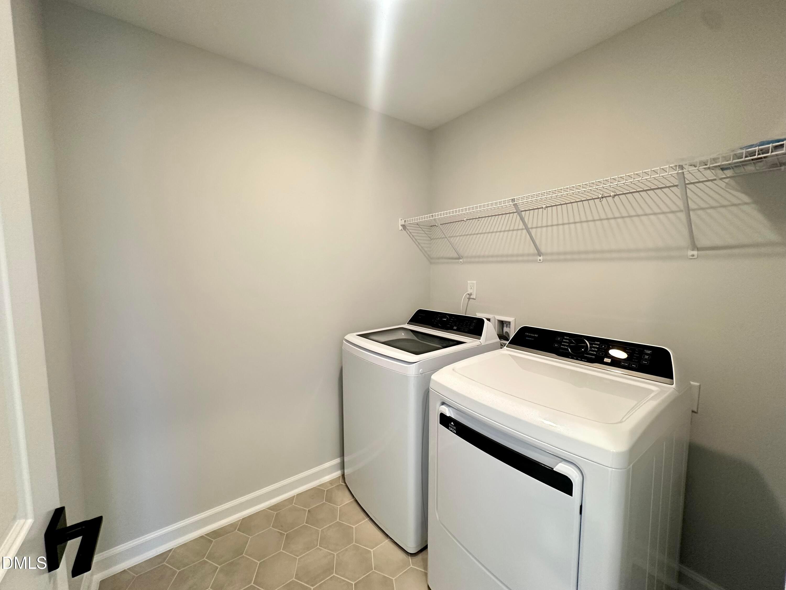 Modern laundry room with white front-load washer, dryer, wire shelving, hex tile floor in Davidson Homes The Avery, Knightdale, NC