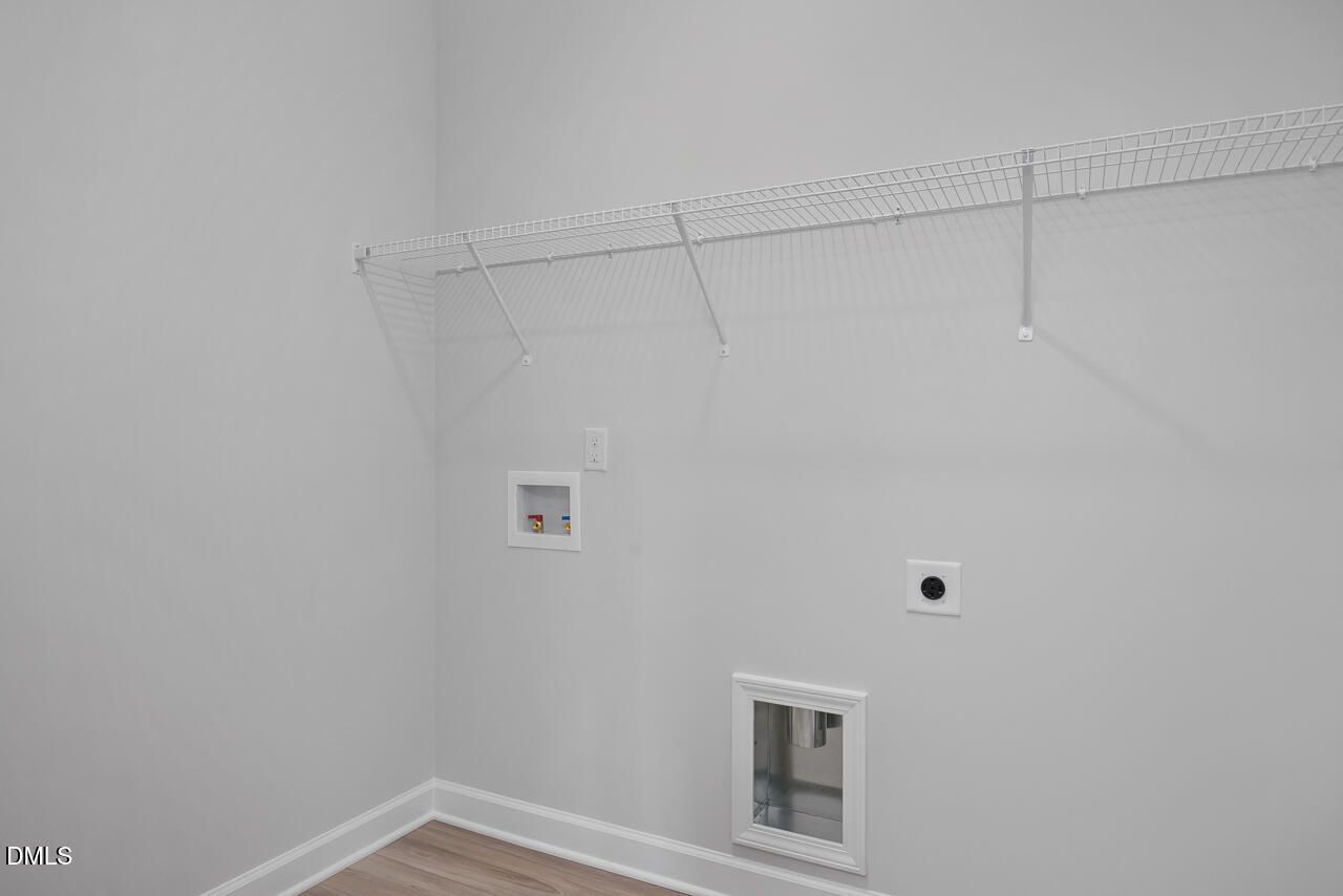 Functional laundry room with white wire shelving, washer-dryer hookups, exhaust vent in The Daphne D by Davidson Homes, Lillington NC