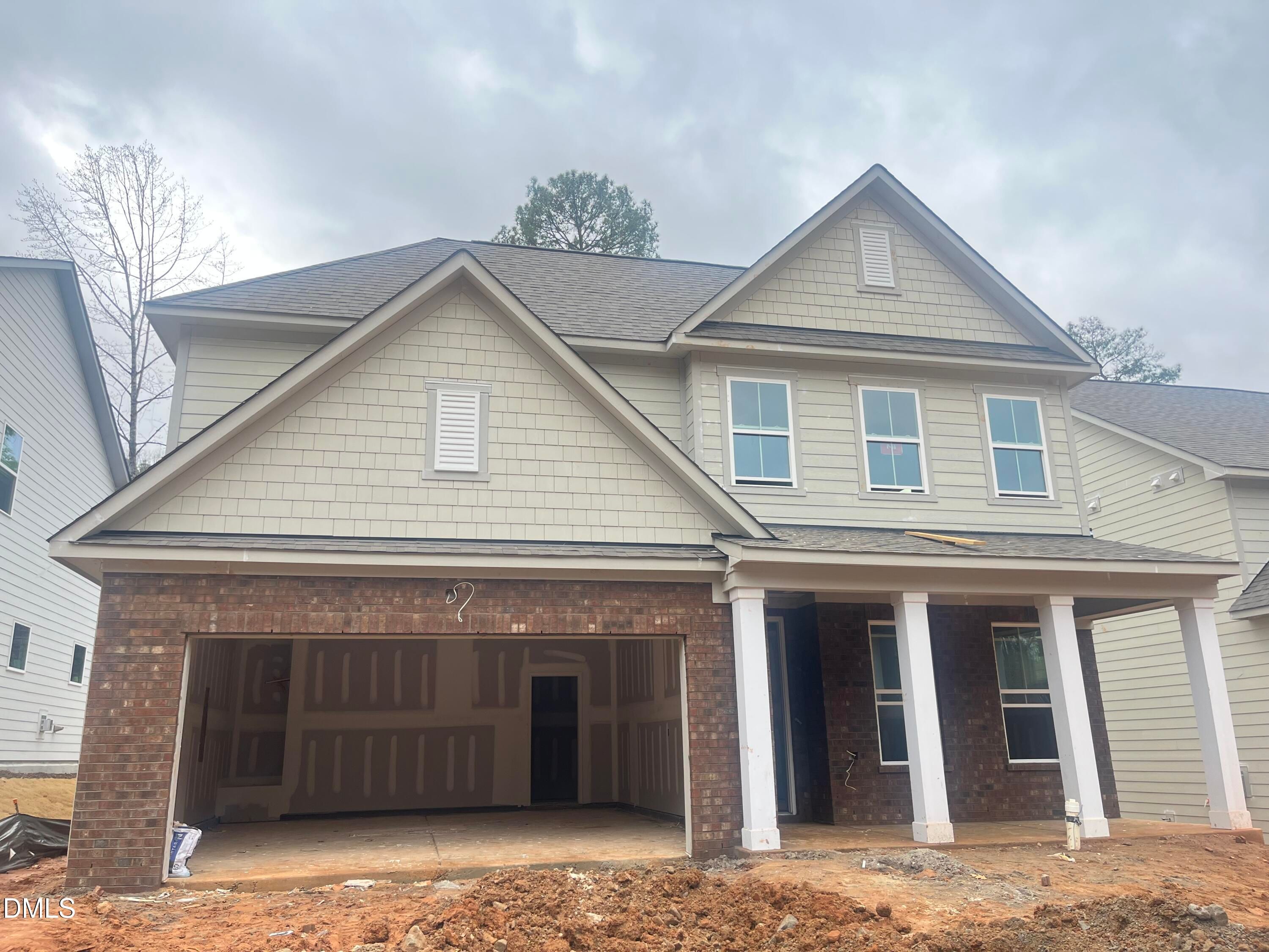 Two-story Ashport L exterior with beige siding, brick garage, open 2-car bay, and columned porch by Davidson Homes in Wake Forest, NC