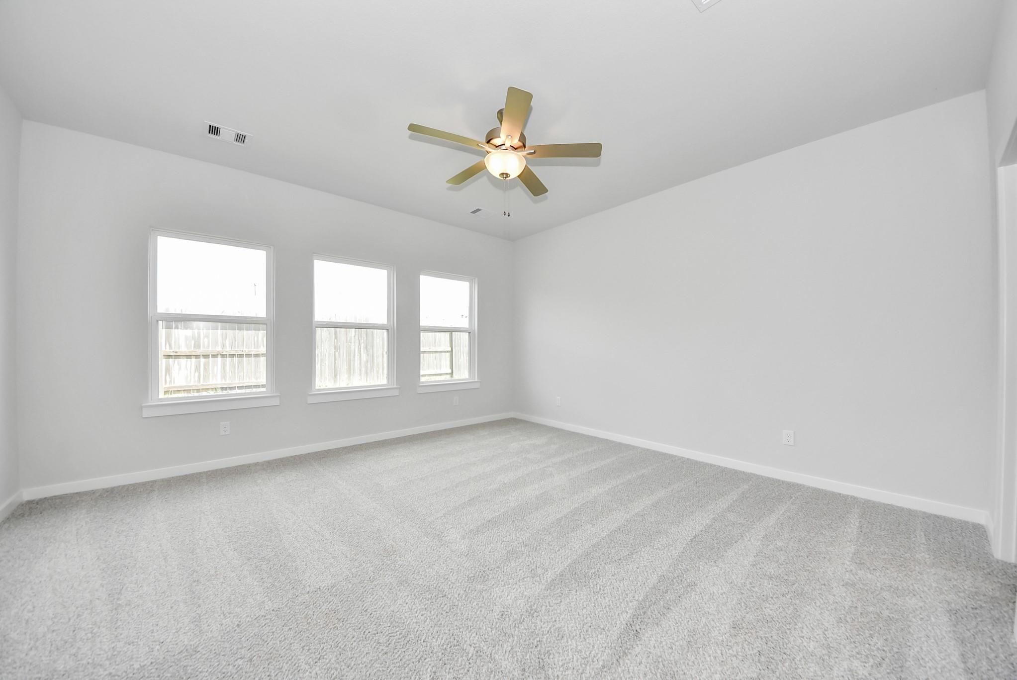 Bright, spacious bedroom with carpet flooring and ceiling fan in The Verano B floor plan by Davidson Homes in Katy, Texas.