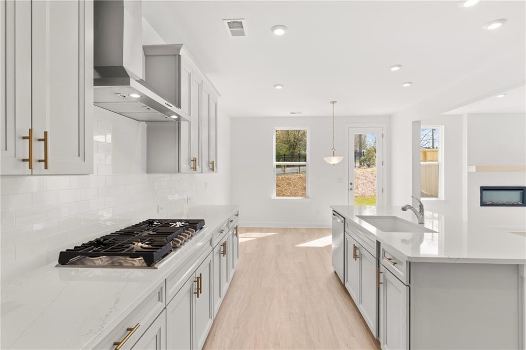 Bright modern kitchen with white cabinets, quartz island, gas range, and backyard views in The Gavin E floor plan, Kennesaw, Georgia