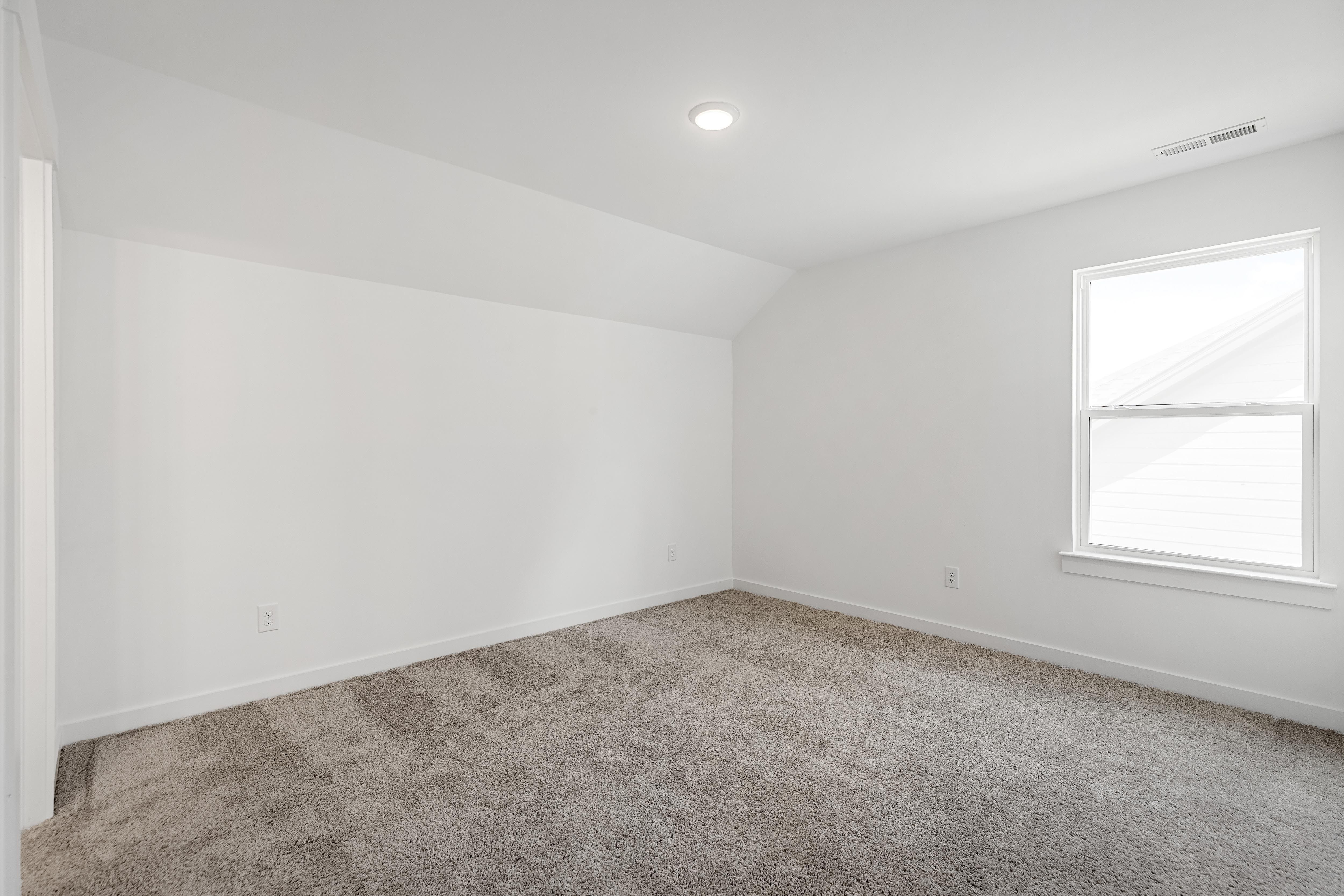 Bright, carpeted bedroom with vaulted ceilings in The Cedar D home design by Davidson Homes.