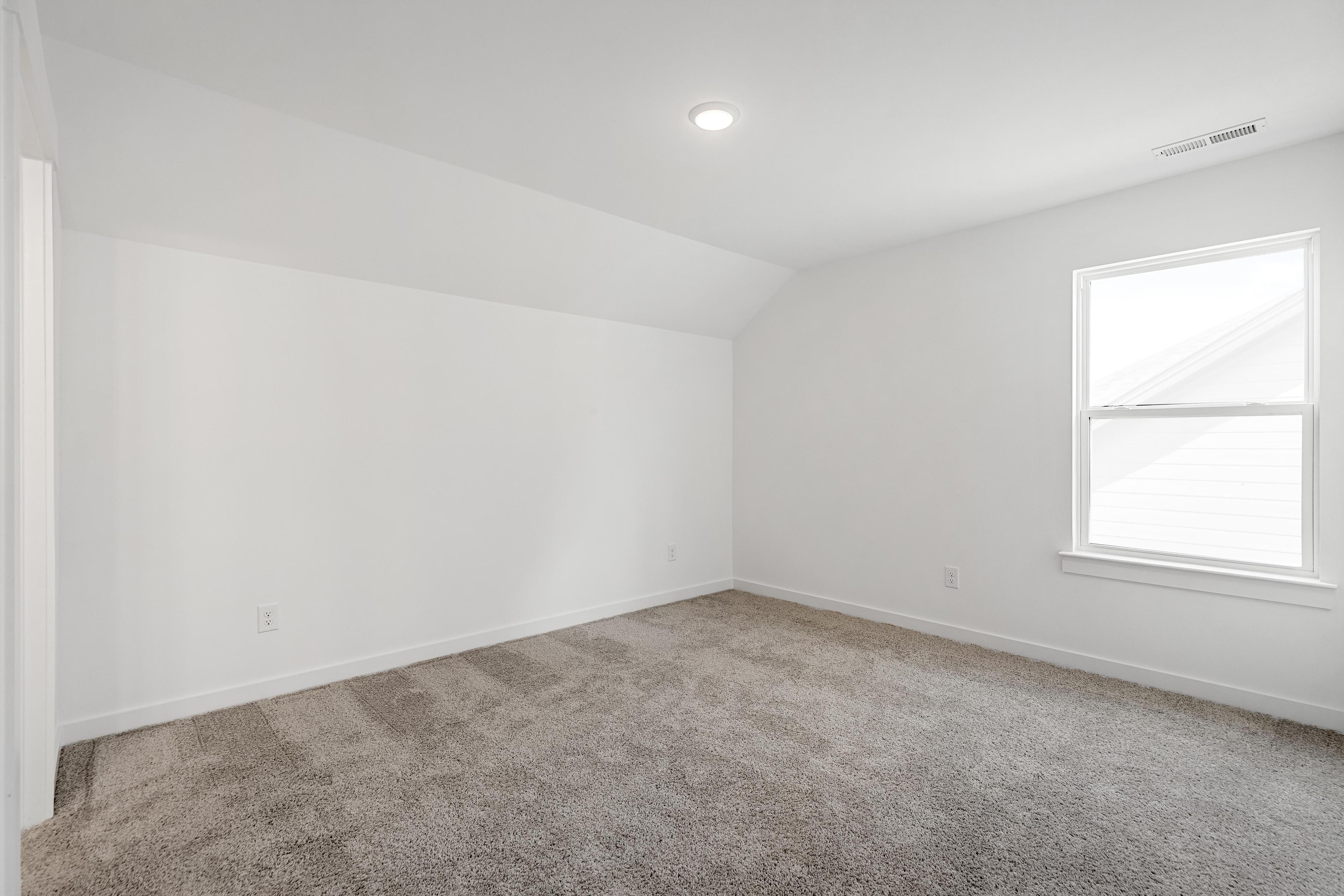 Bright, carpeted bedroom with vaulted ceilings in The Cedar D home design by Davidson Homes.