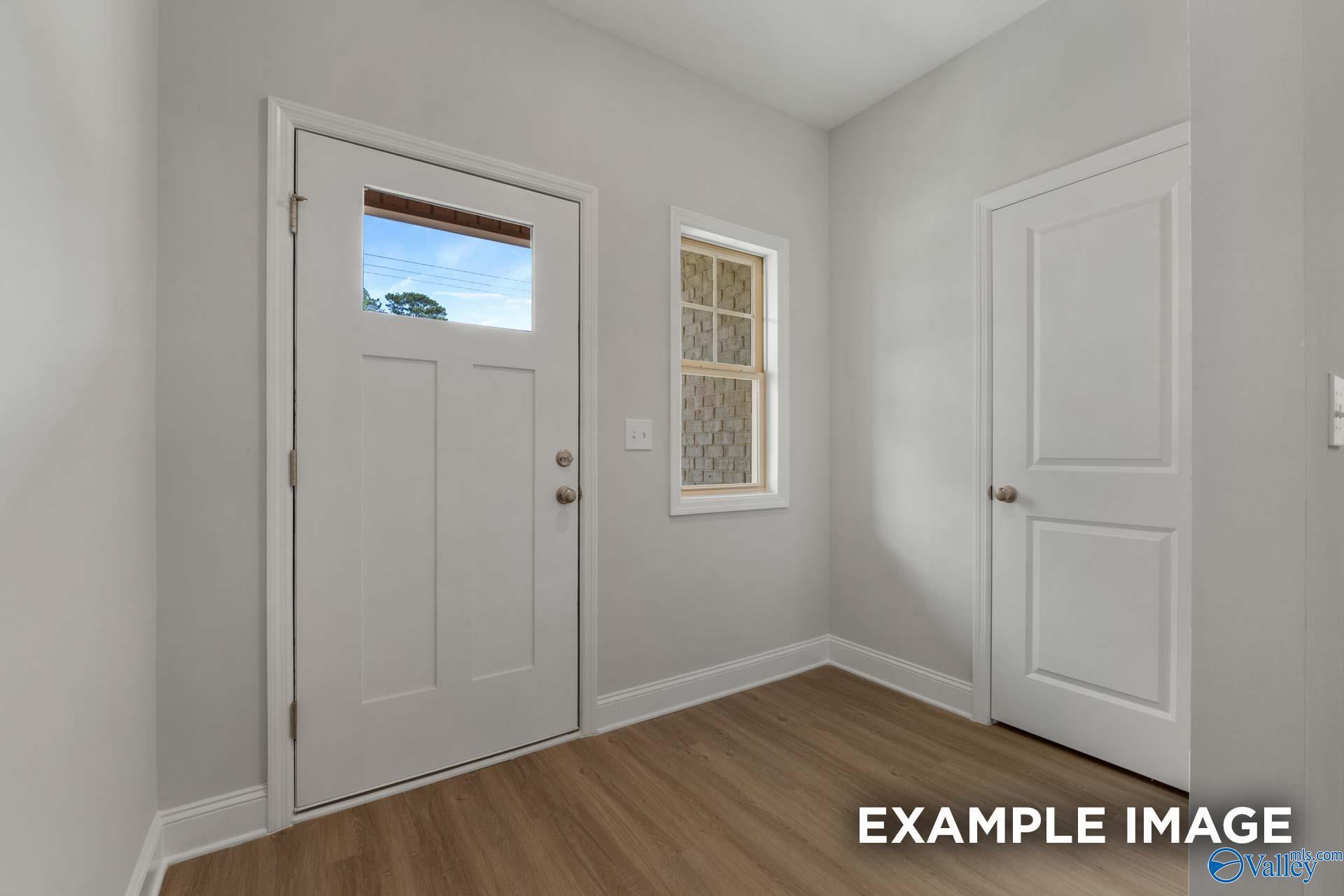 Bright entryway with white paneled doors, sidelight window, and light wood floors in The Camilla B floor plan, Hartselle, Alabama