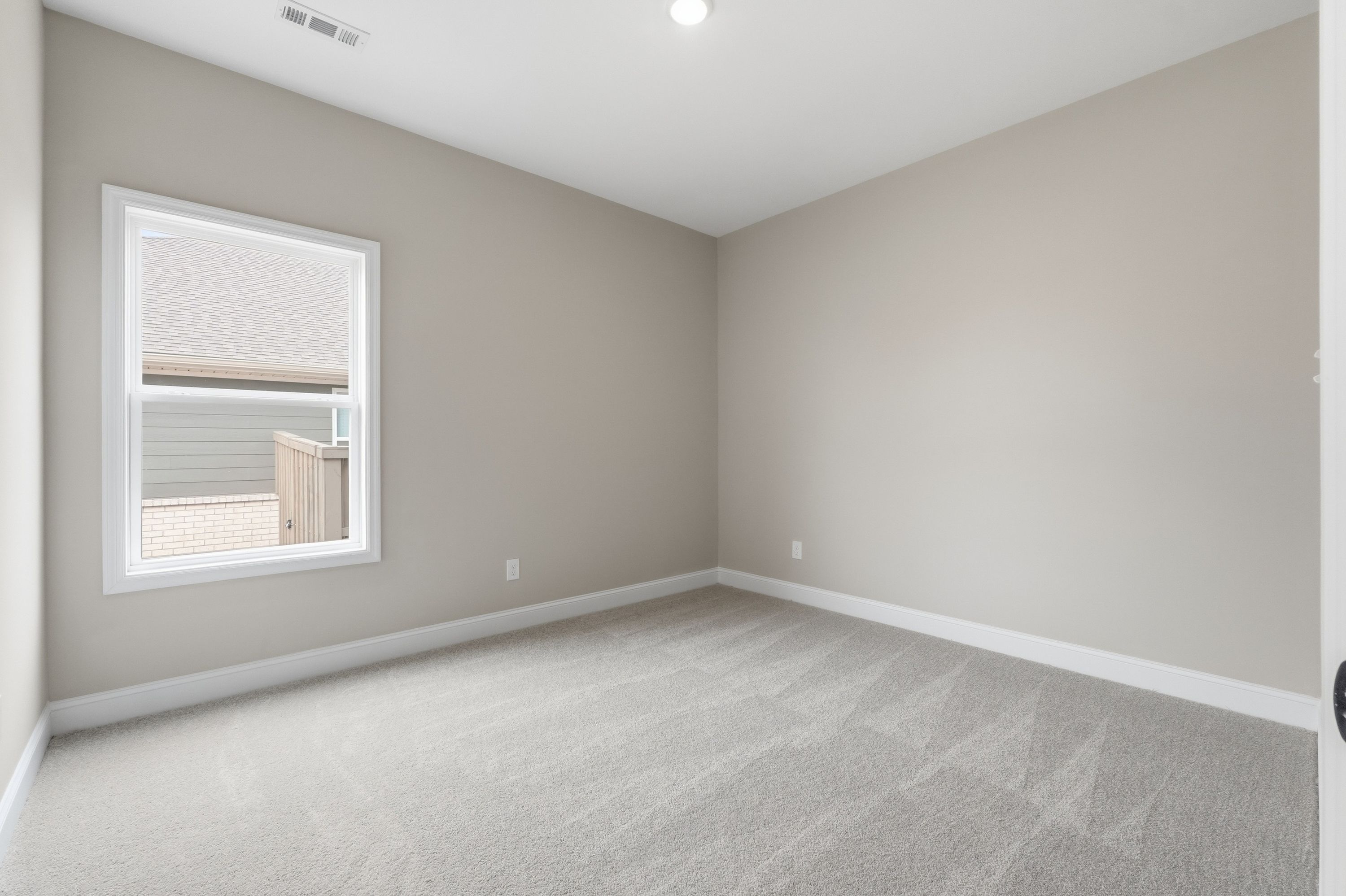 Spacious bedroom in The Rockford home design by Davidson Homes, Cullman AL, with beige walls, carpet floors, large window